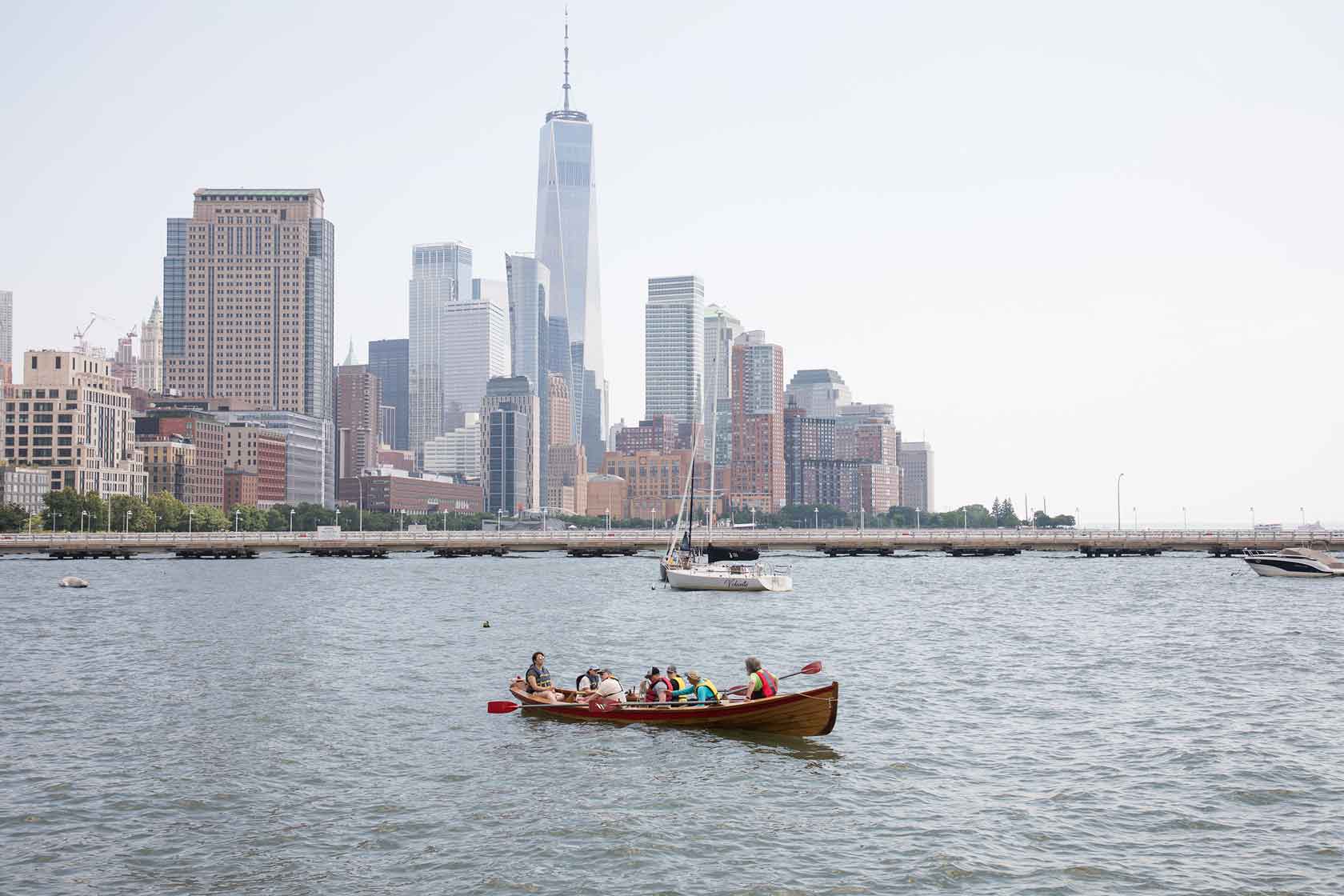 A group grab their paddles and begin rowing in the Hudson River