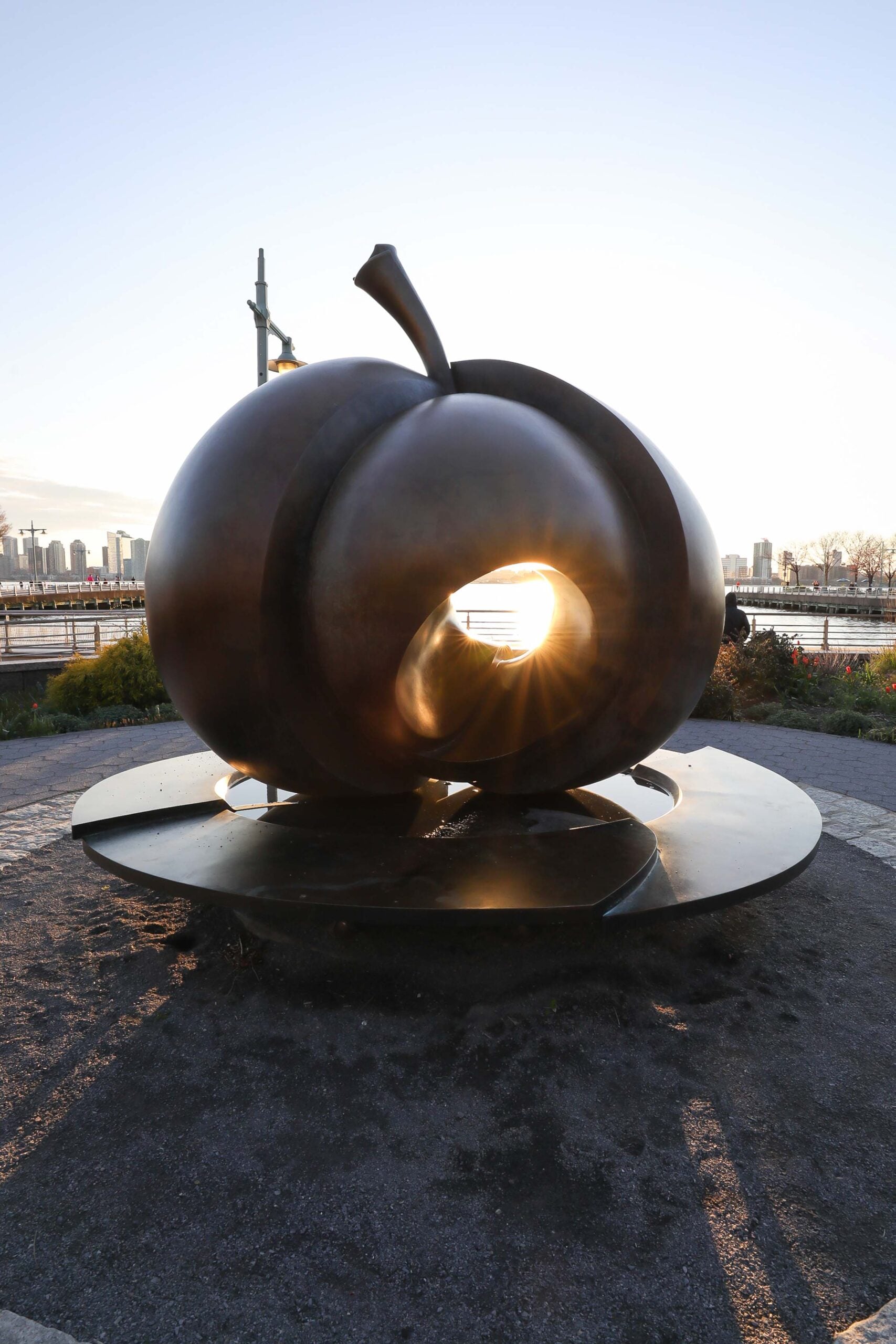 The sunset glow peers through the core of The Apple statue in Hudson River Park