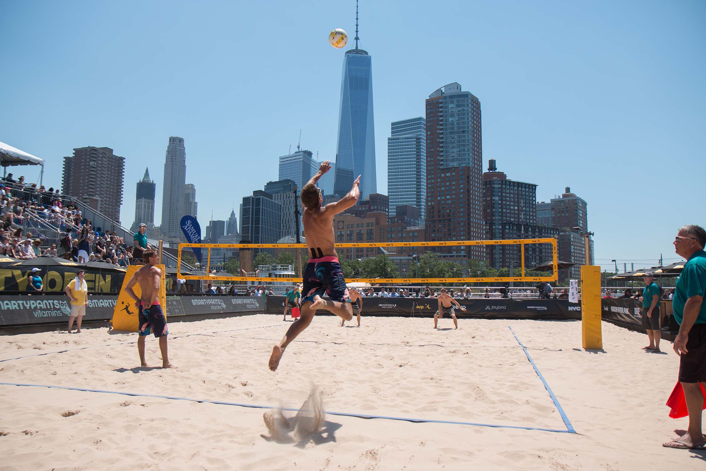 A volleyball player jumps and flies towards the ball to hit it over the net