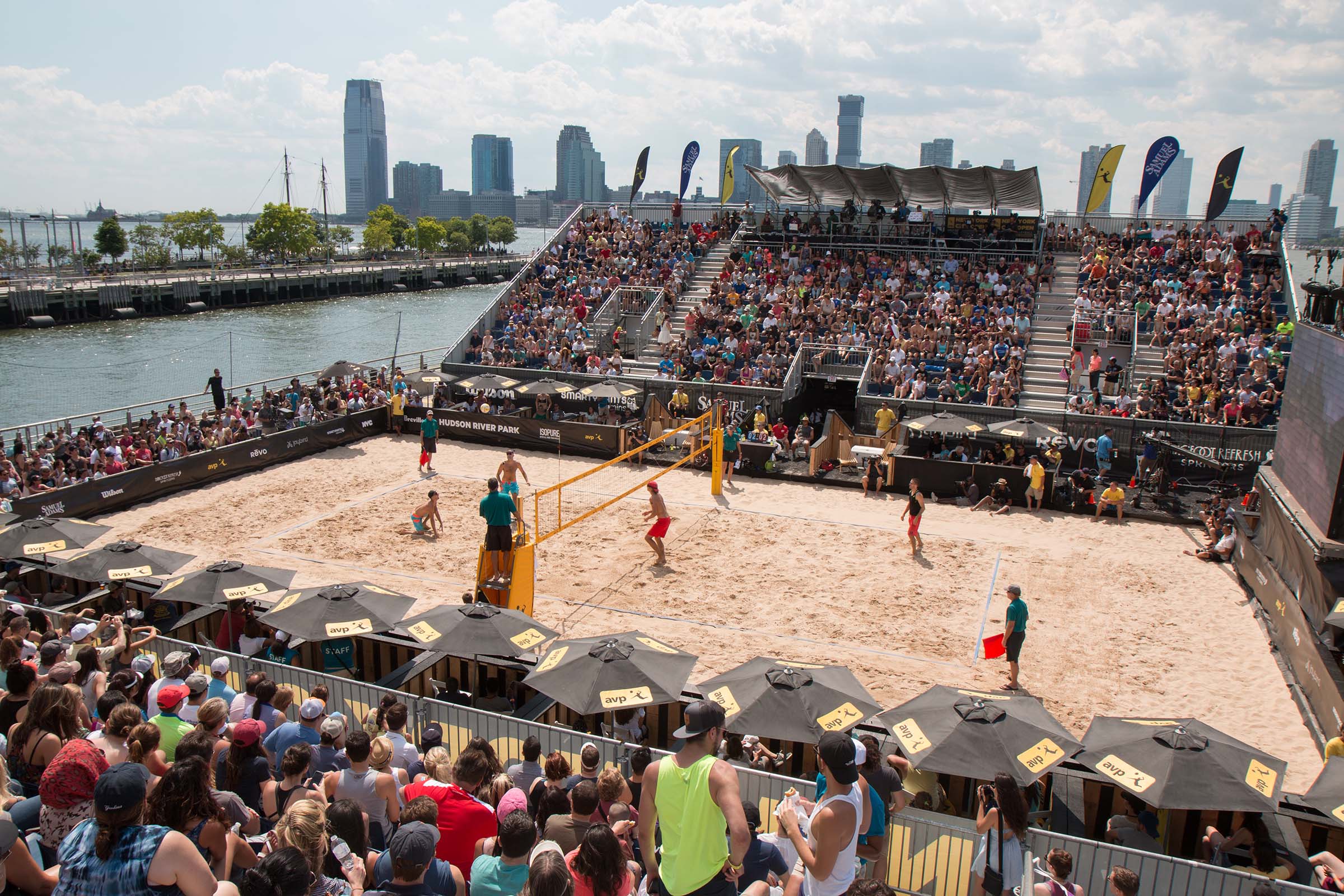 An overhead view of the whole sandy volleyball court with the two teams on either side of the net