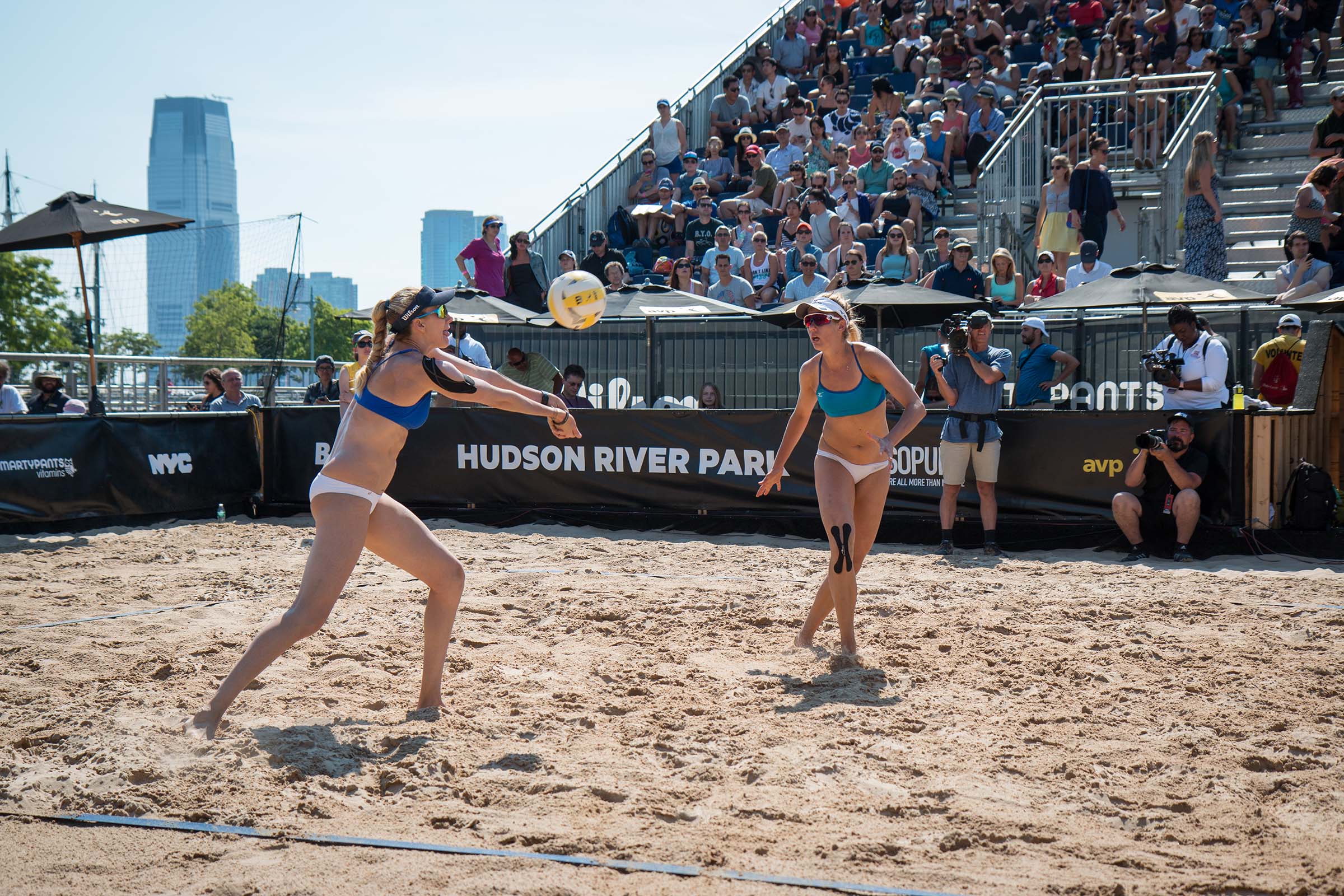 A volleyball player rushes to hit the ball over the net
