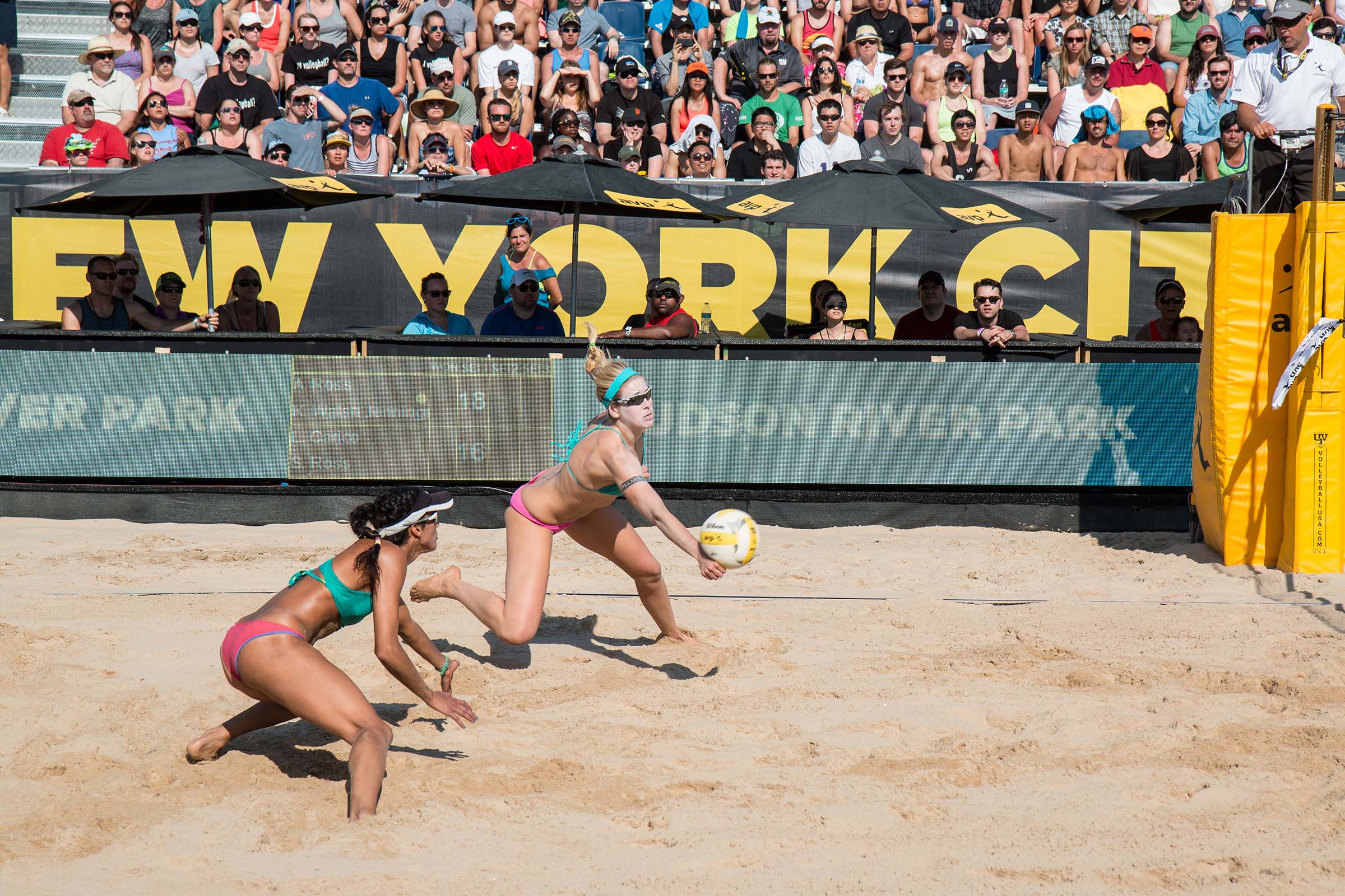 A volleyball player and her teammate crouch to hit the ball