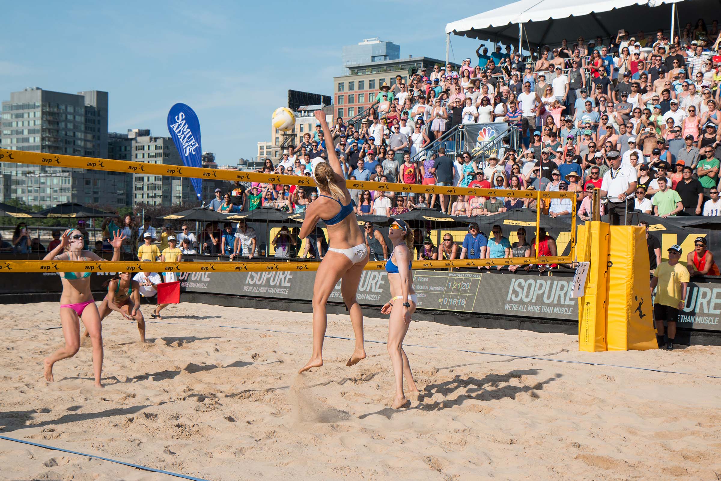 A volleyball player rushes to hit the ball over the net