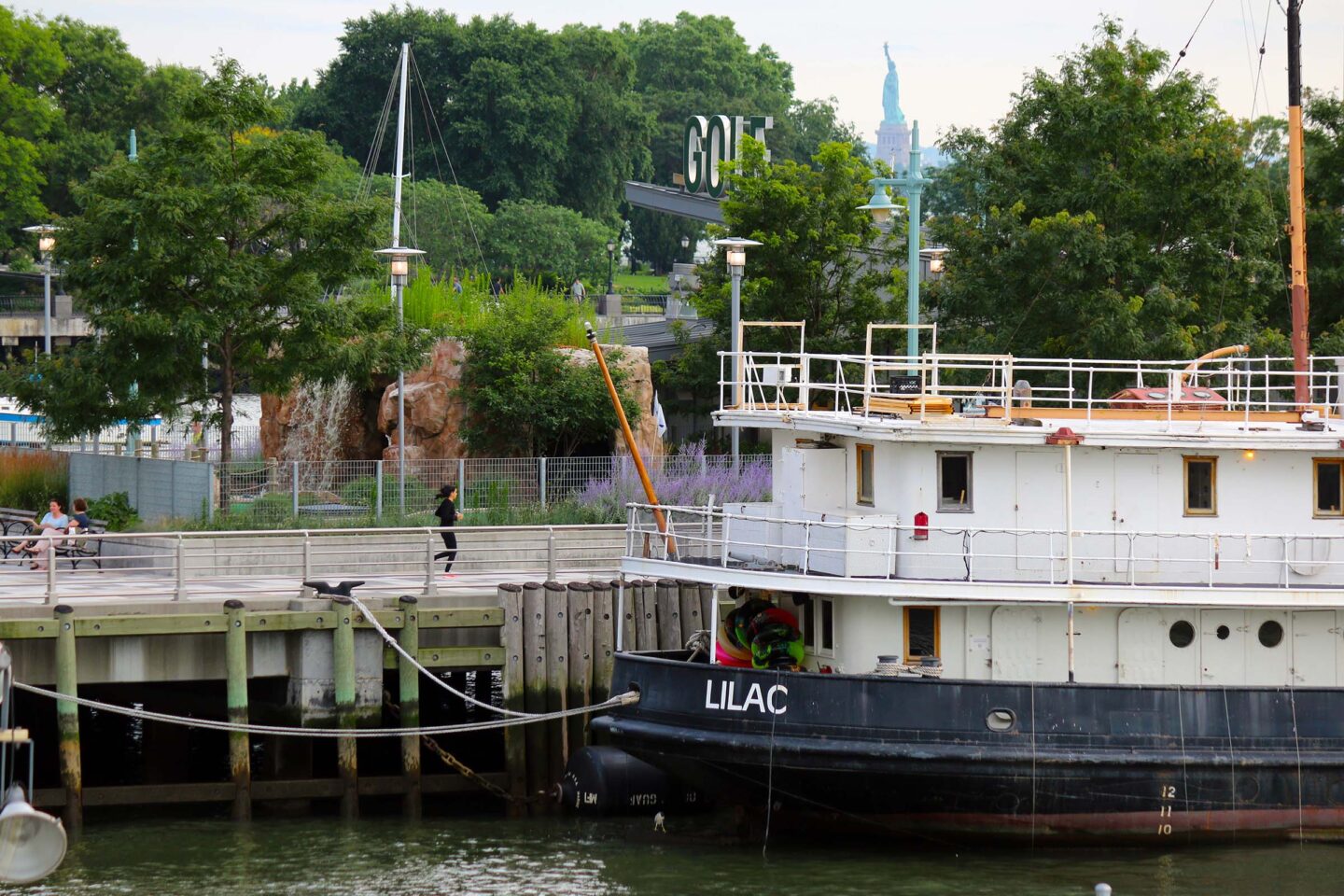 The Lilac, a historical vessel, docked at Pier 25 with the Statue of Liberty visible in the distance