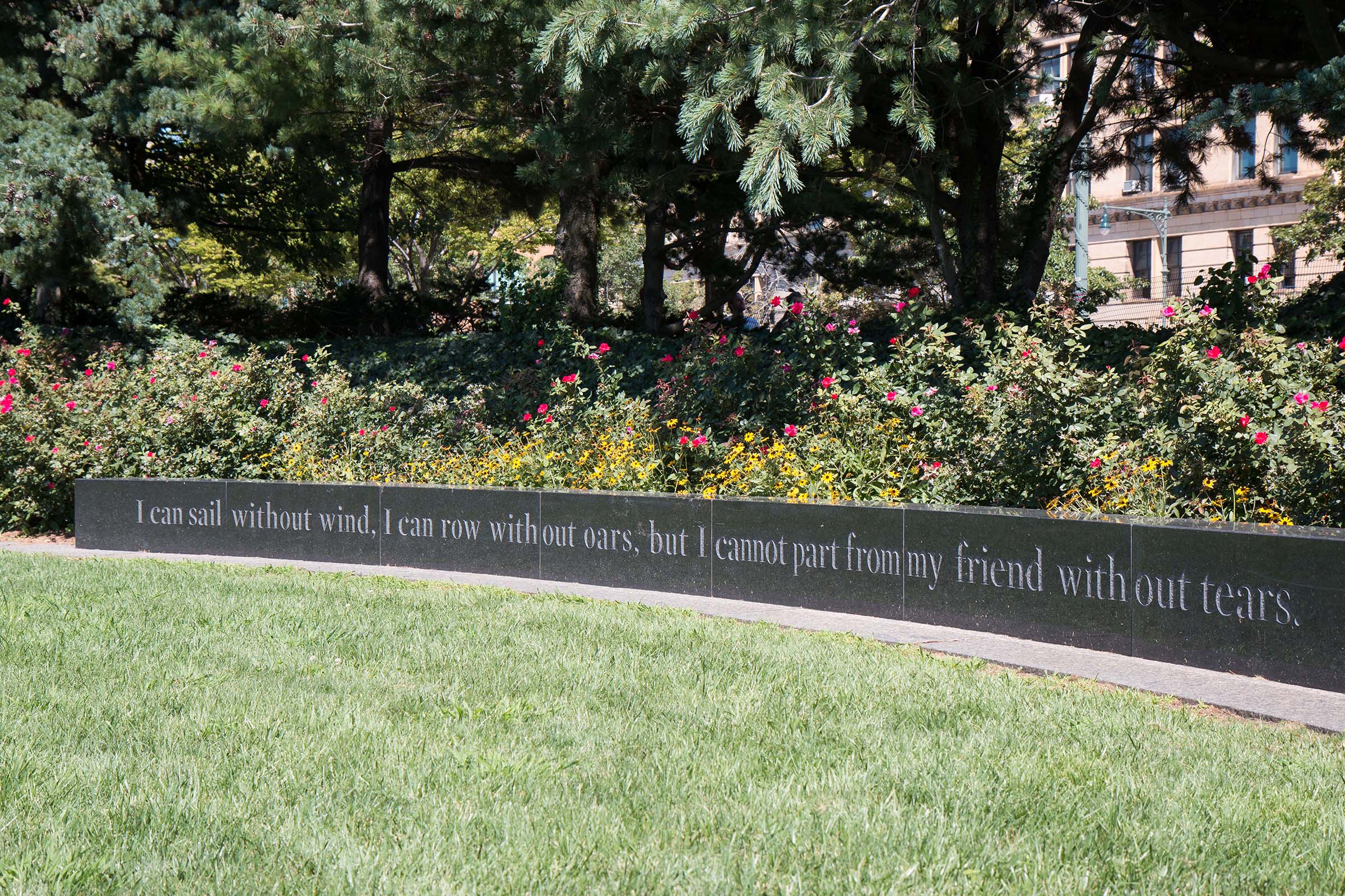 The AIDS Memorial in Hudson River Park, showing a low wall with text engraved: "I can sail without wind, I can row without oars, but I cannot part from my friend without tears"