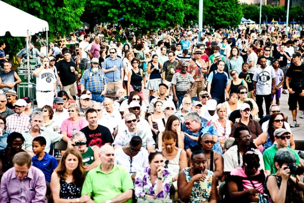 A crowd of Blues enthusiast sit on the lawn waiting the performance to begin
