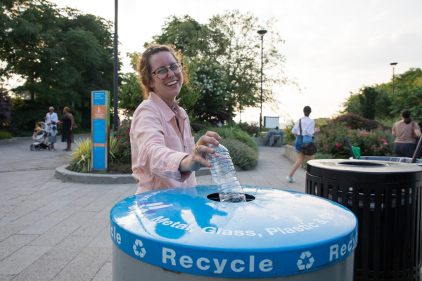 A Park visitor throws a plastic bottle into a recycling bin