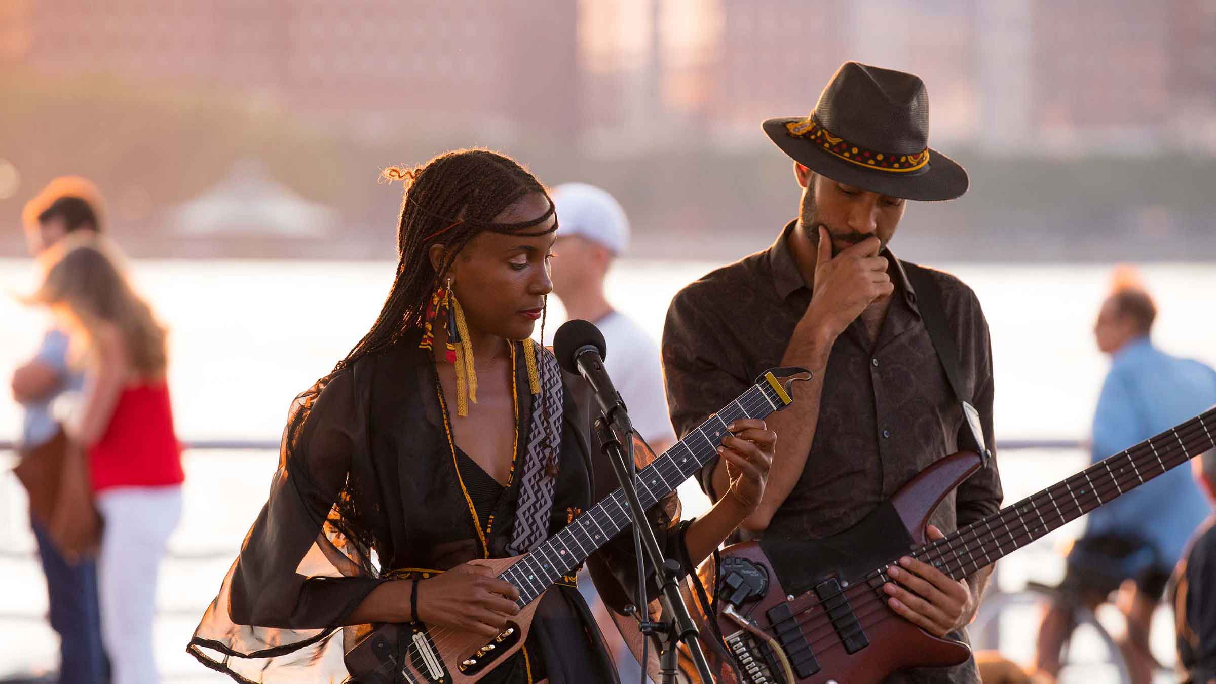 Duo Koku Gonza perform as the sunsets in the distance. Both strum guitars