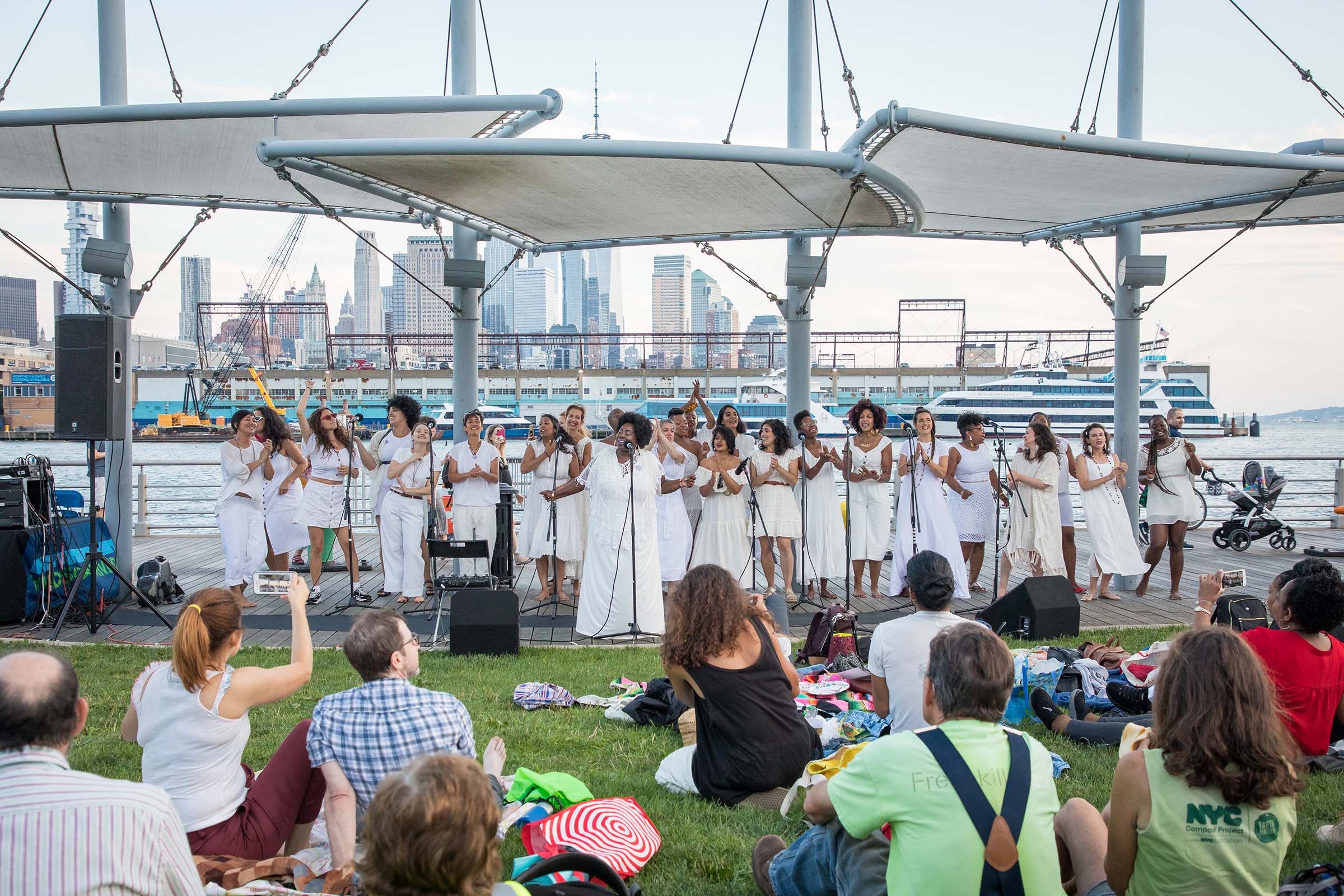 A group of singers dressed in white sing out to the Park visitors at Sunset on the Hudson