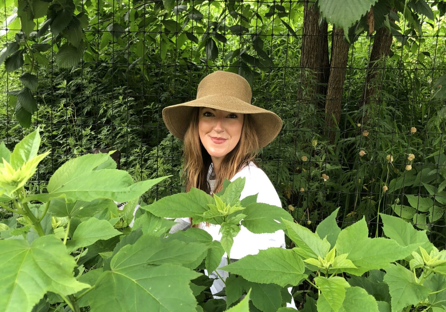 A person smiling for the camera while working in a planted area during a volunteer event