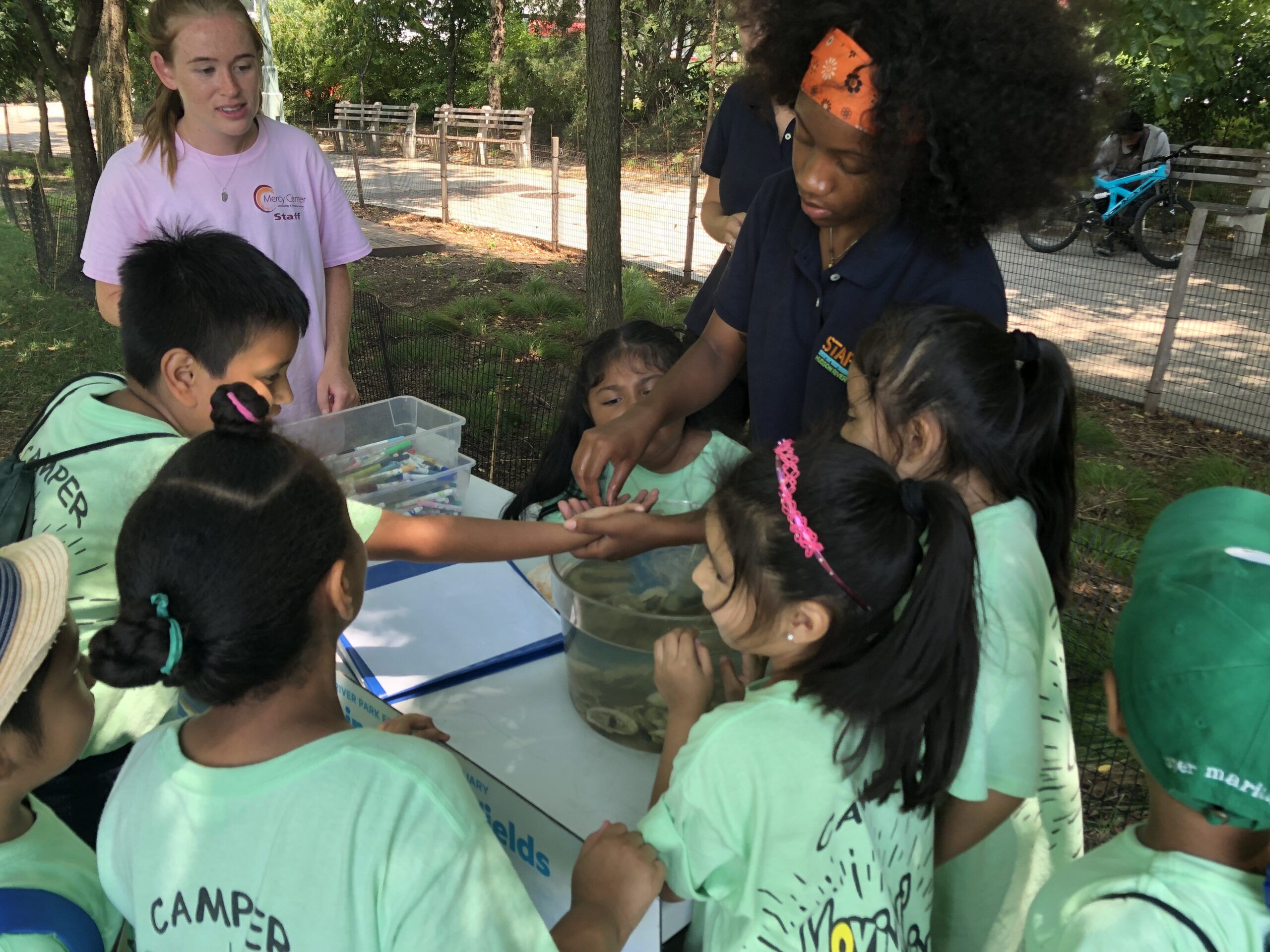 A group of students in green shirts hold oysters