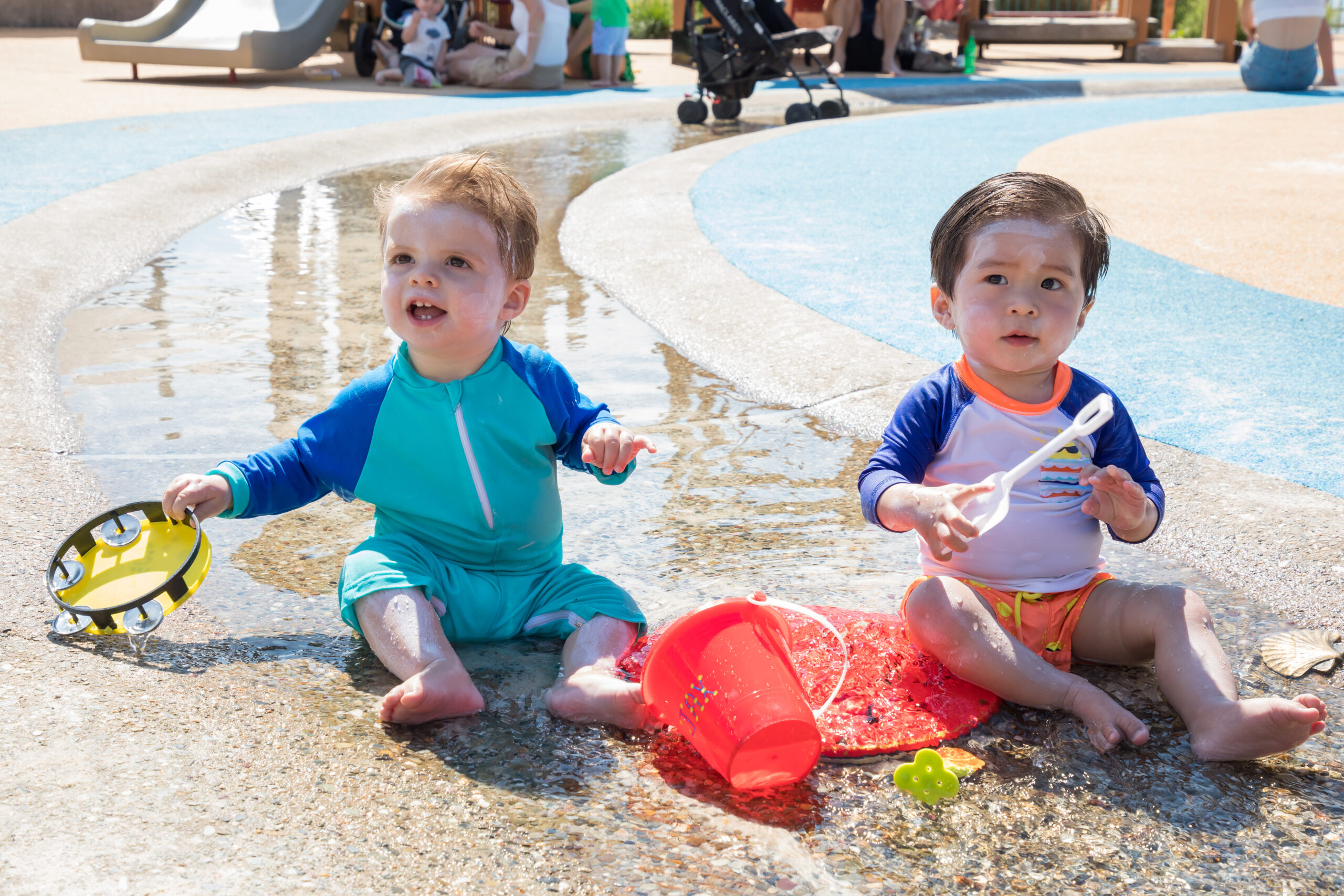 Two tots playing with beach buckets at the Pier 51 Play Area at HRPK