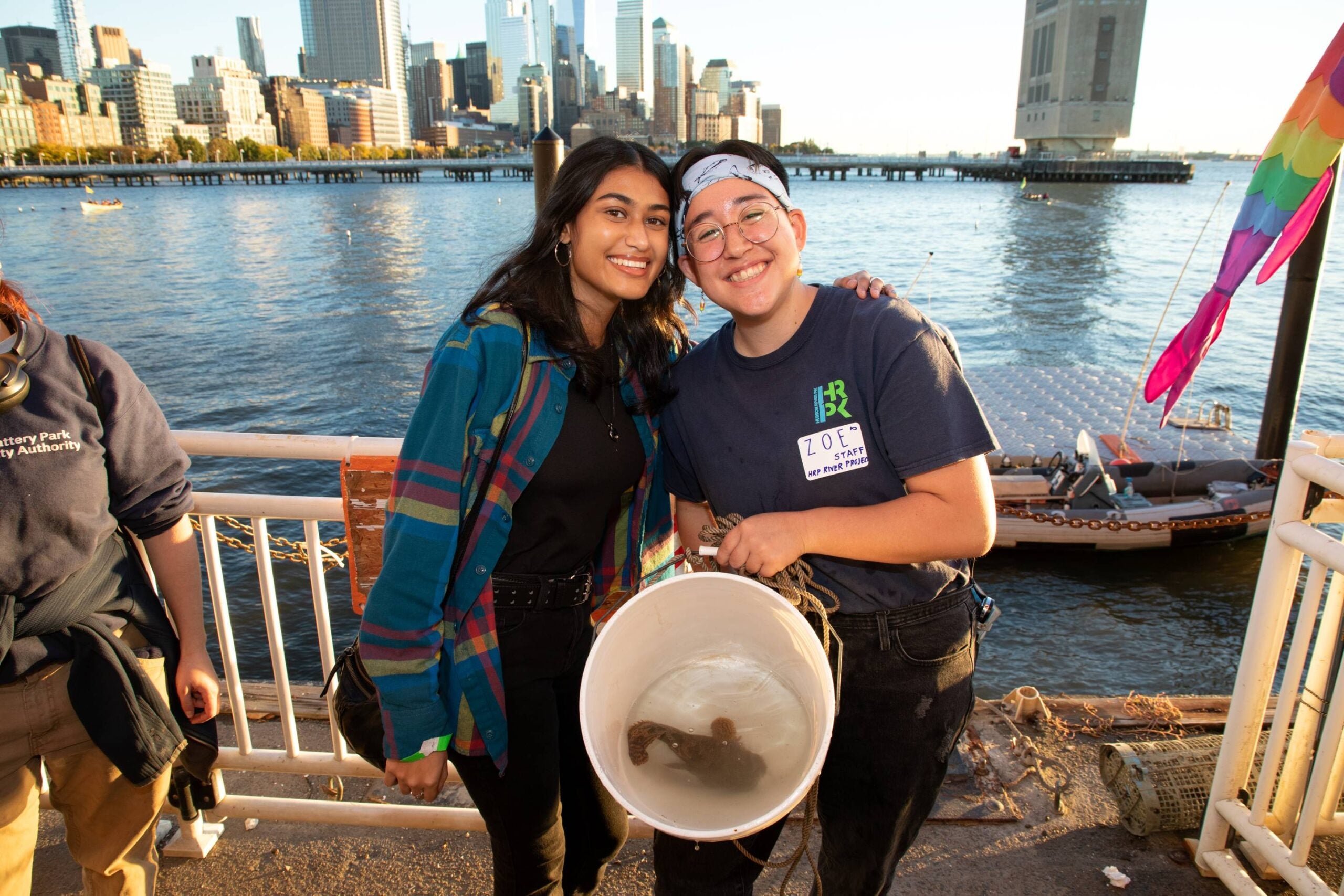 Two HRPK River Project staffers holding a bucket with a fish inside