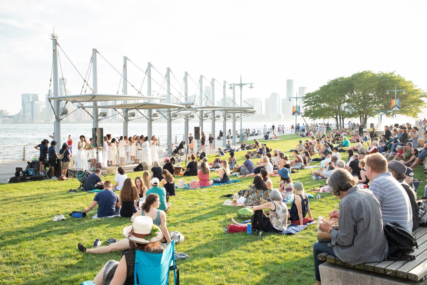 Sunset on the Hudson - Resistance Revival Chorus performs for a crowd on grass at golden hour on Pier 45