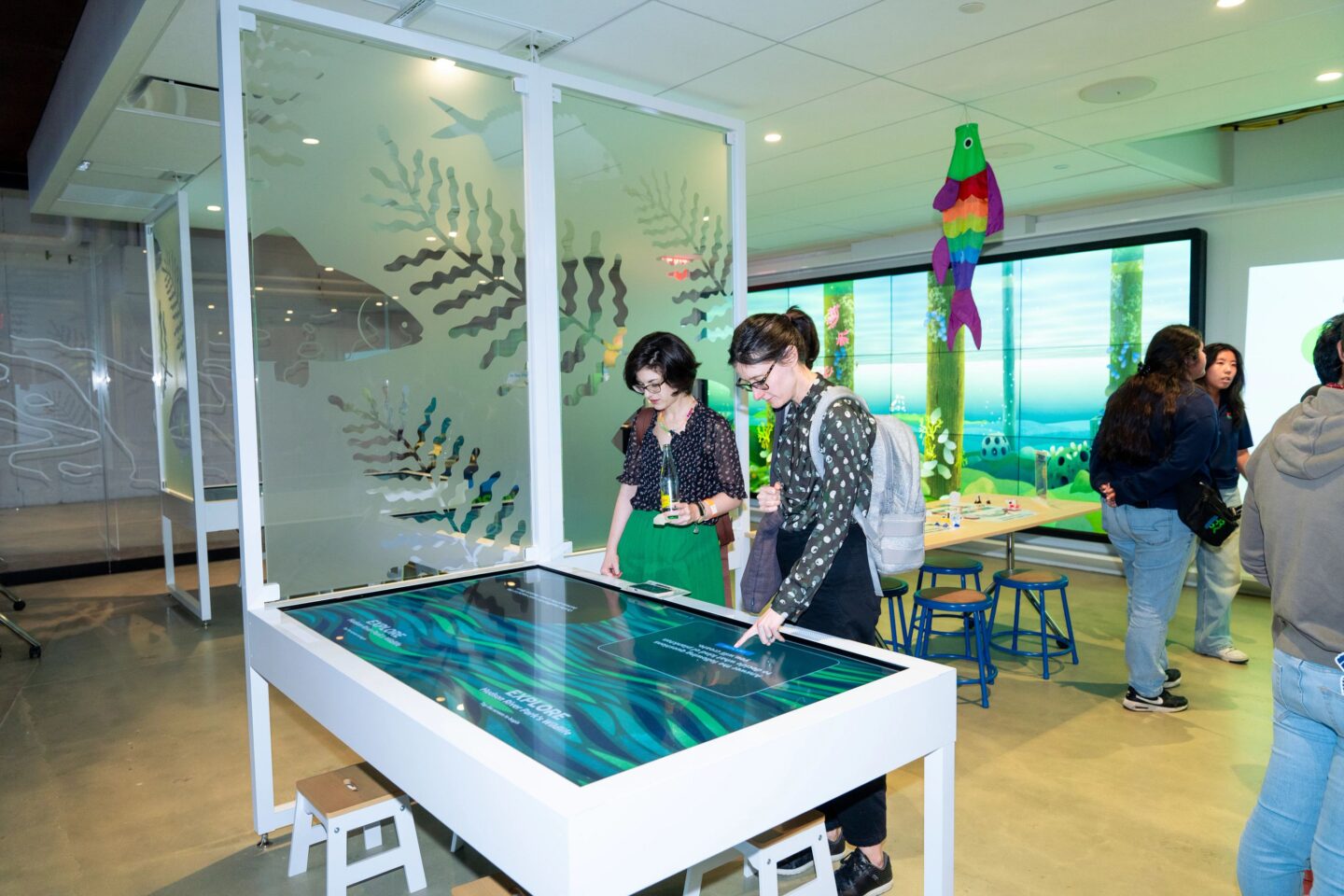 Two people interact with a tabletop touchscreen display at the Pier 57 Discovery Tank