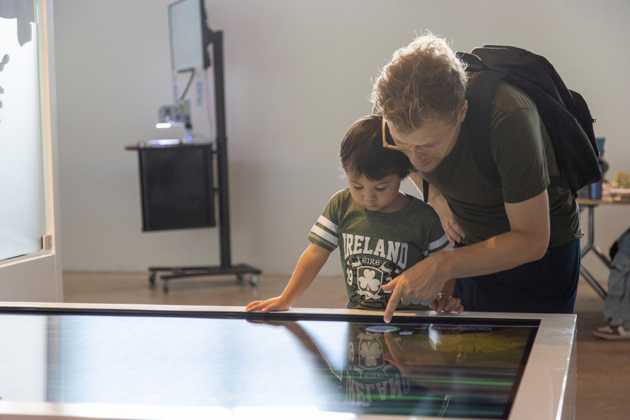A parent and a child interact with a touchscreen display at the Pier 57 Discovery Tank