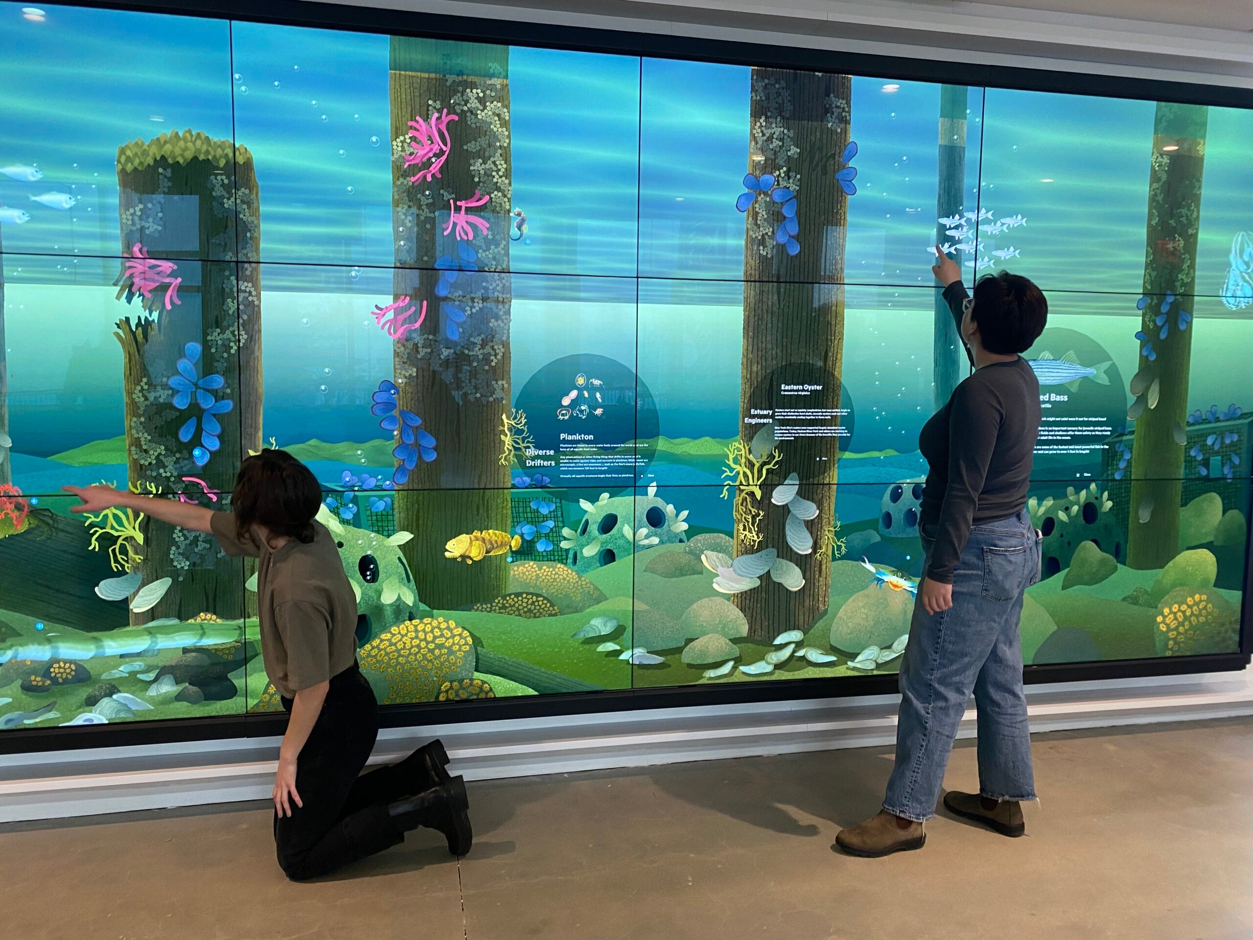 Two people play with interactive features at the Discovery Tank at Pier 57