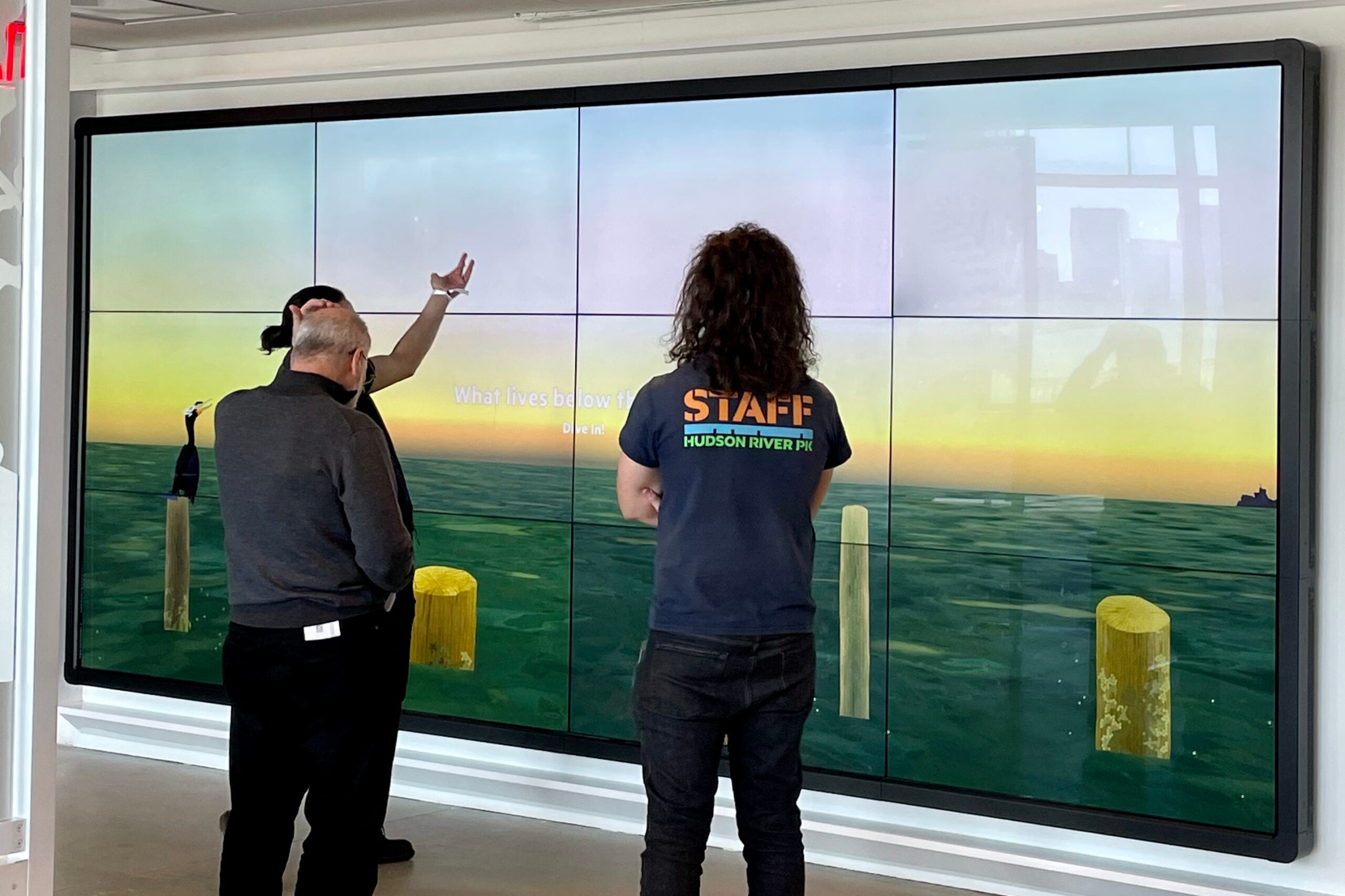 River Project Educators interact with guests in front of the Discovery Tank's interactive touchscreen