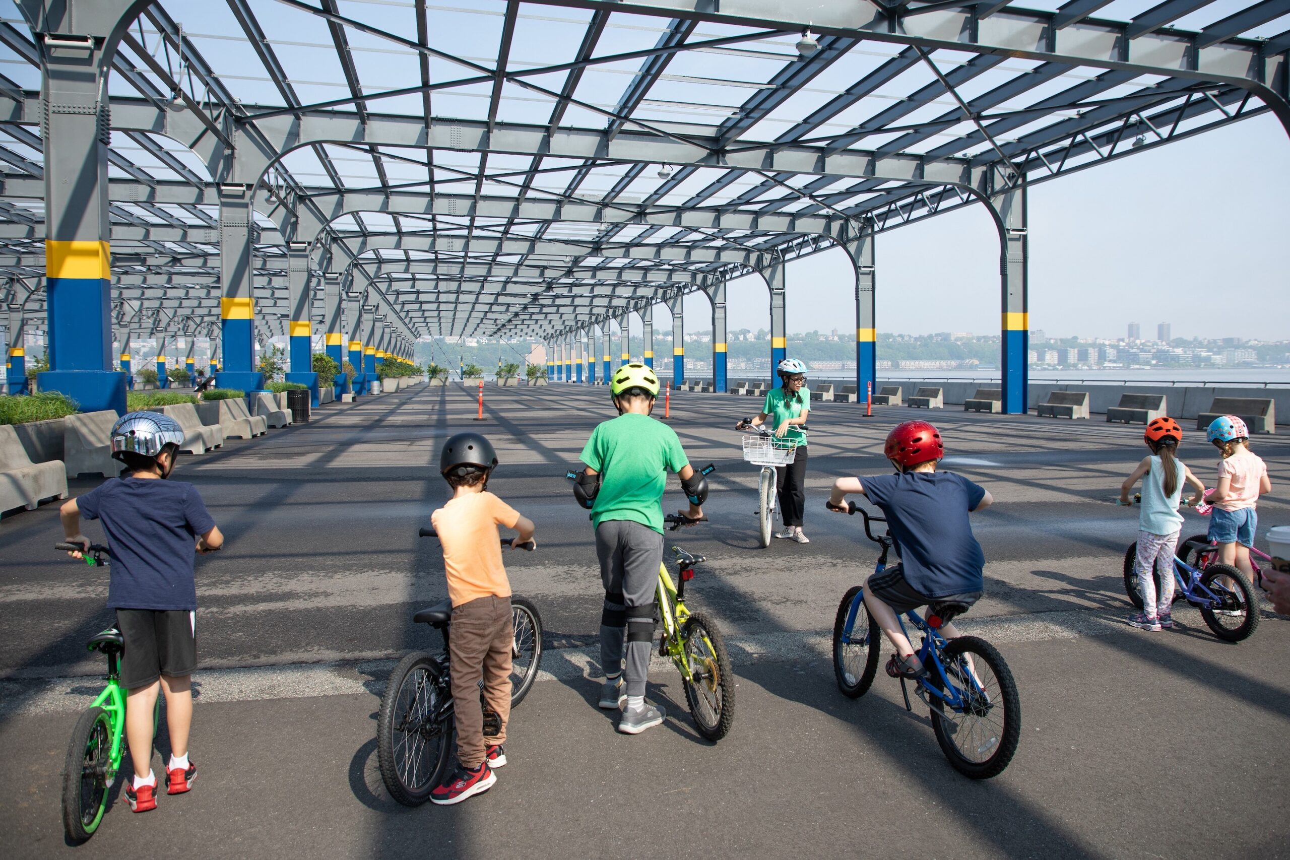 A Bike New York Bike Skills 101 instructor speaking to a line of kids on bikes at Pier 76