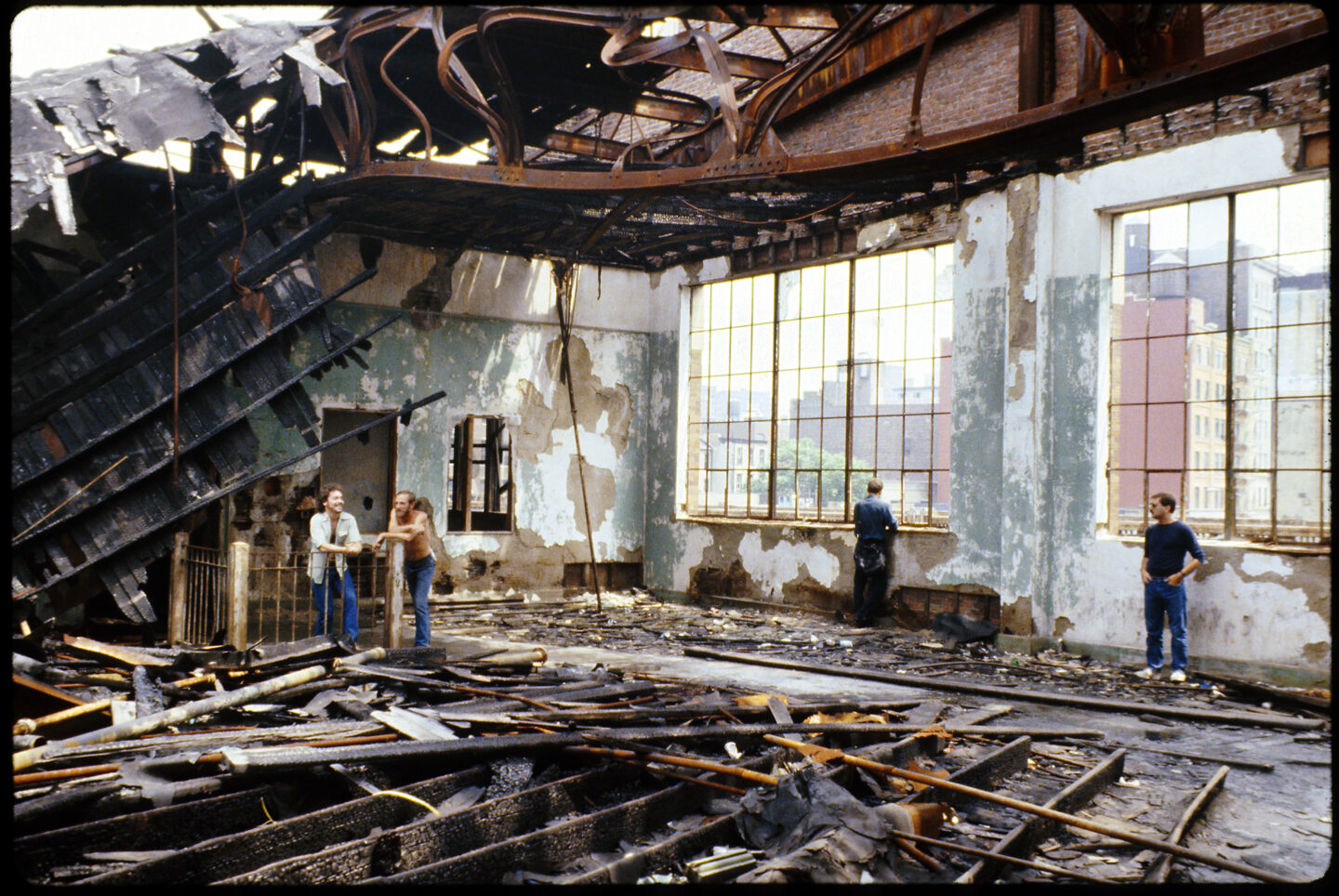A group of men hanging out inside an abandoned and collapsing pier building