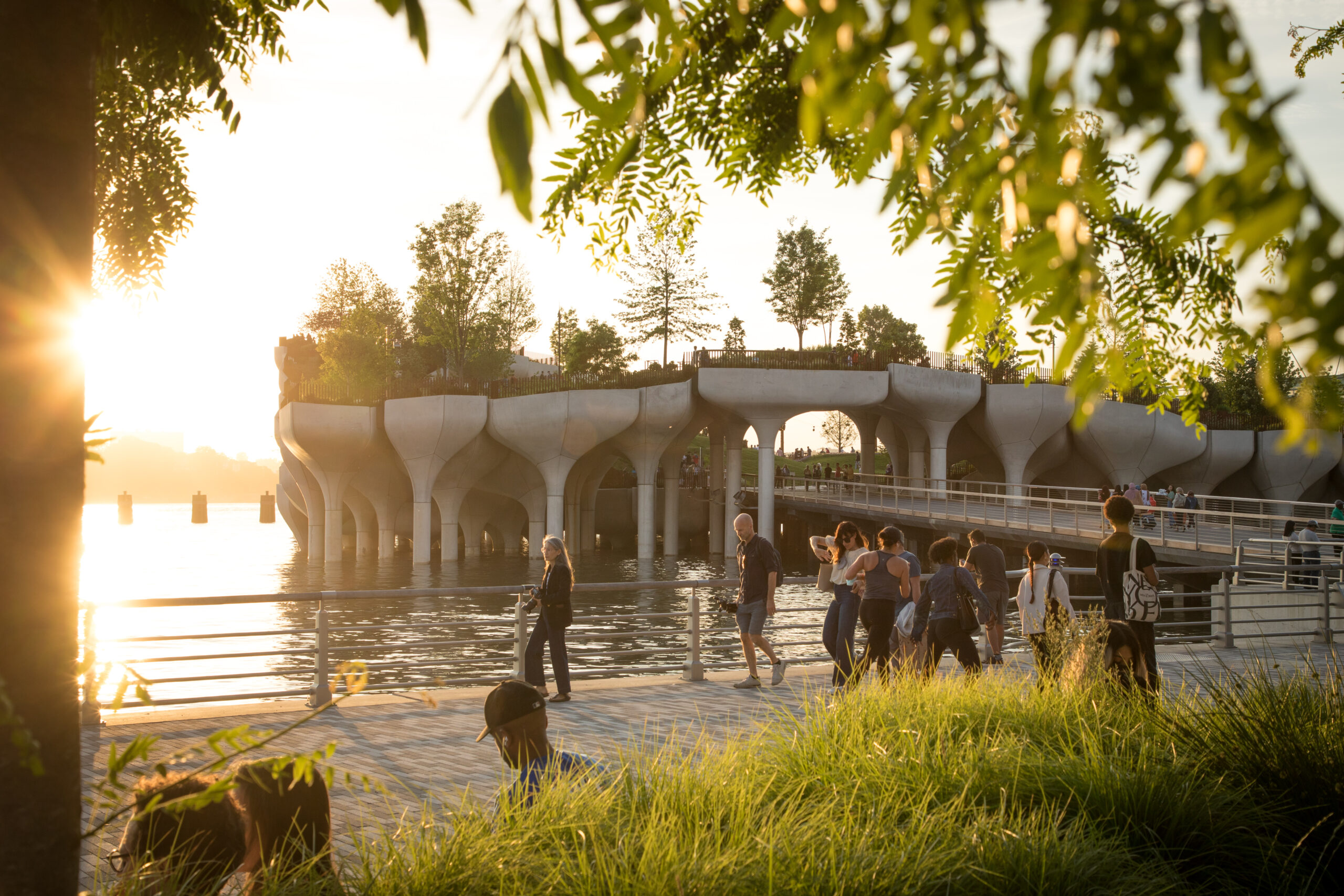 Little Island at sunset with people walking on the esplanade in the foreground.