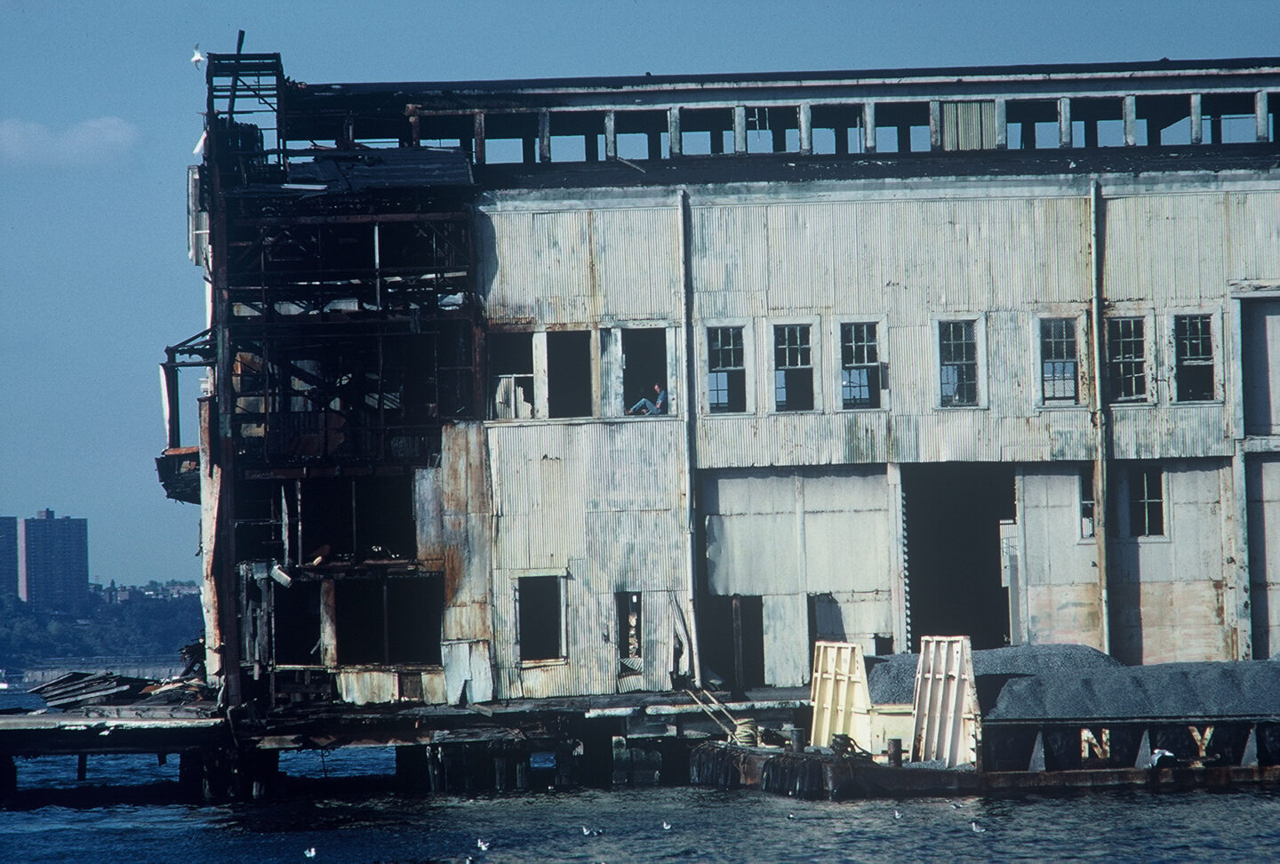 A man sitting inside a window of a dilapidated pier building