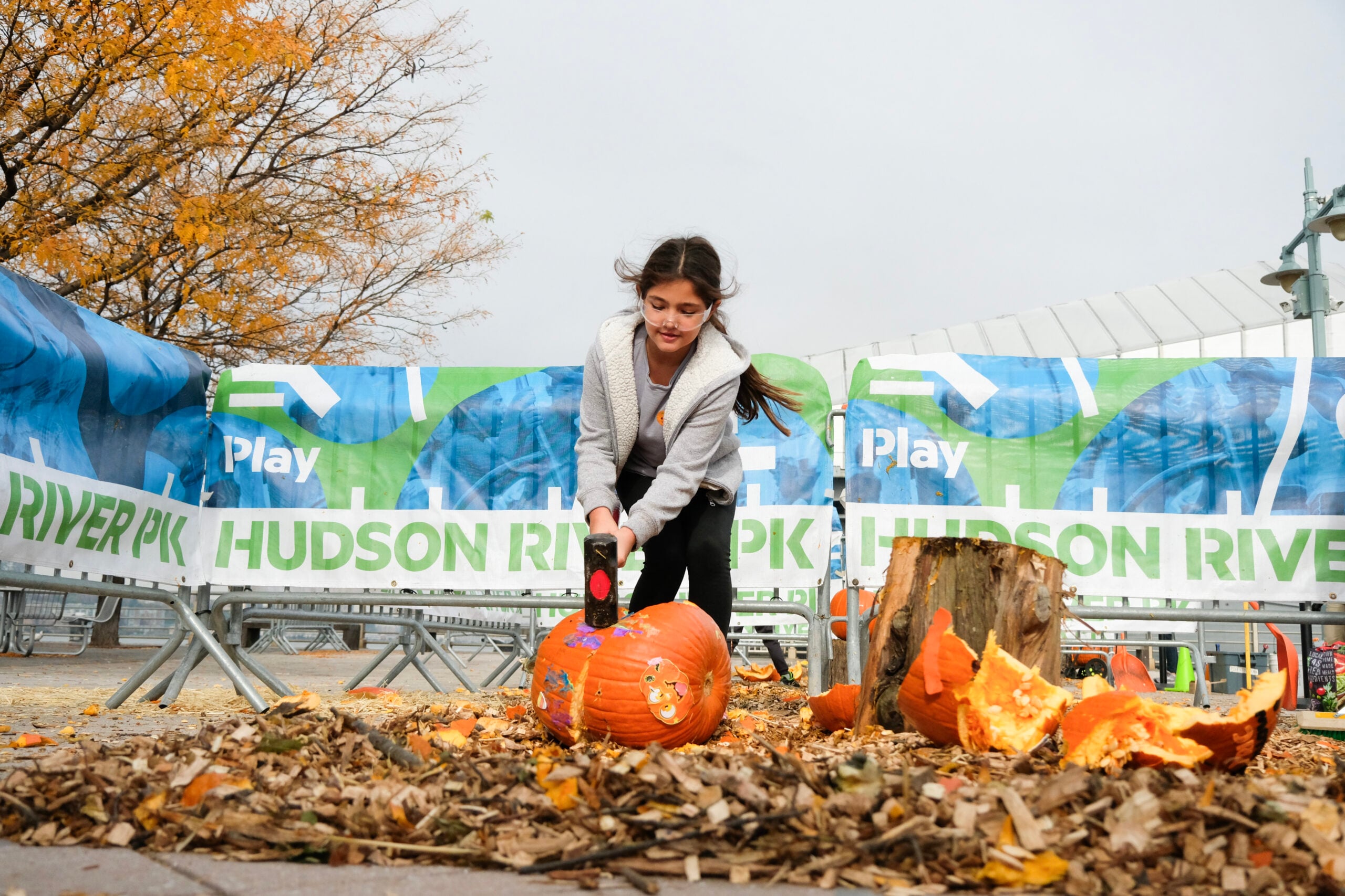 A girl hitting a pumpkin with a sledgehammer at HRPK's Pumpkin Smash event at Pier 84