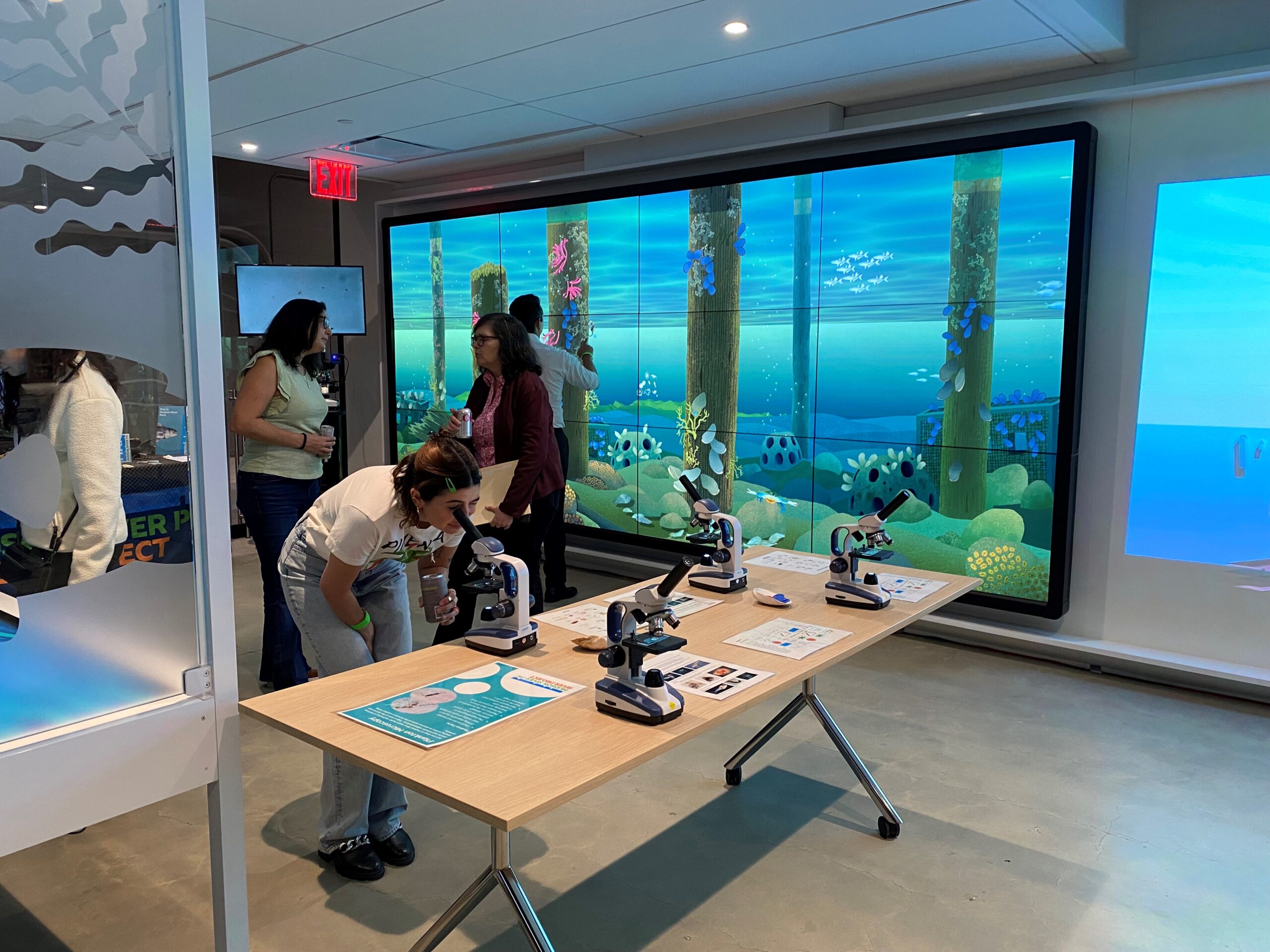 Visitors to the Pier 57 Discovery Tank interact with microscopes and touchscreen displays