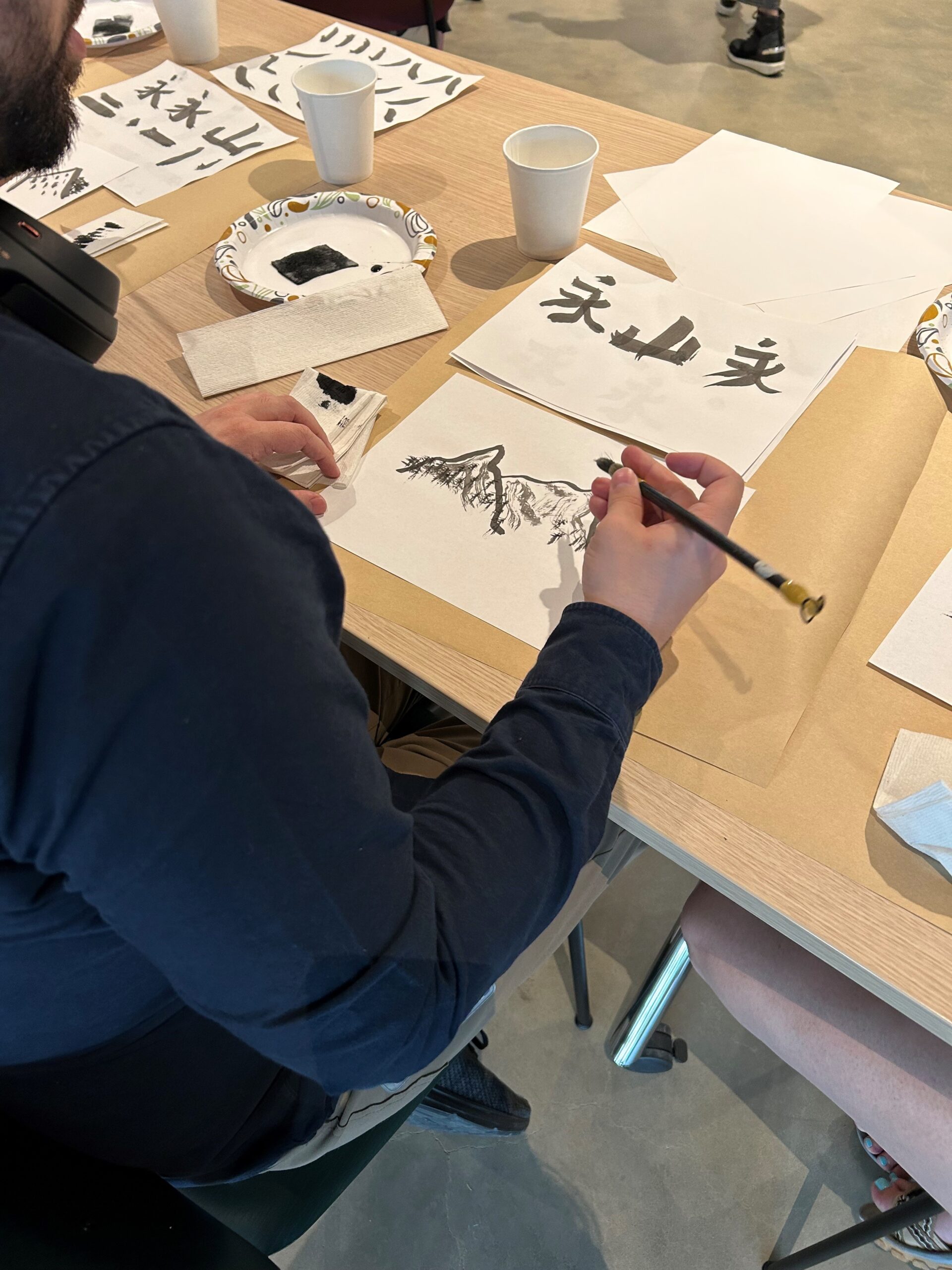 A student painting a mountain scene with watercolors at a Painting Nature event