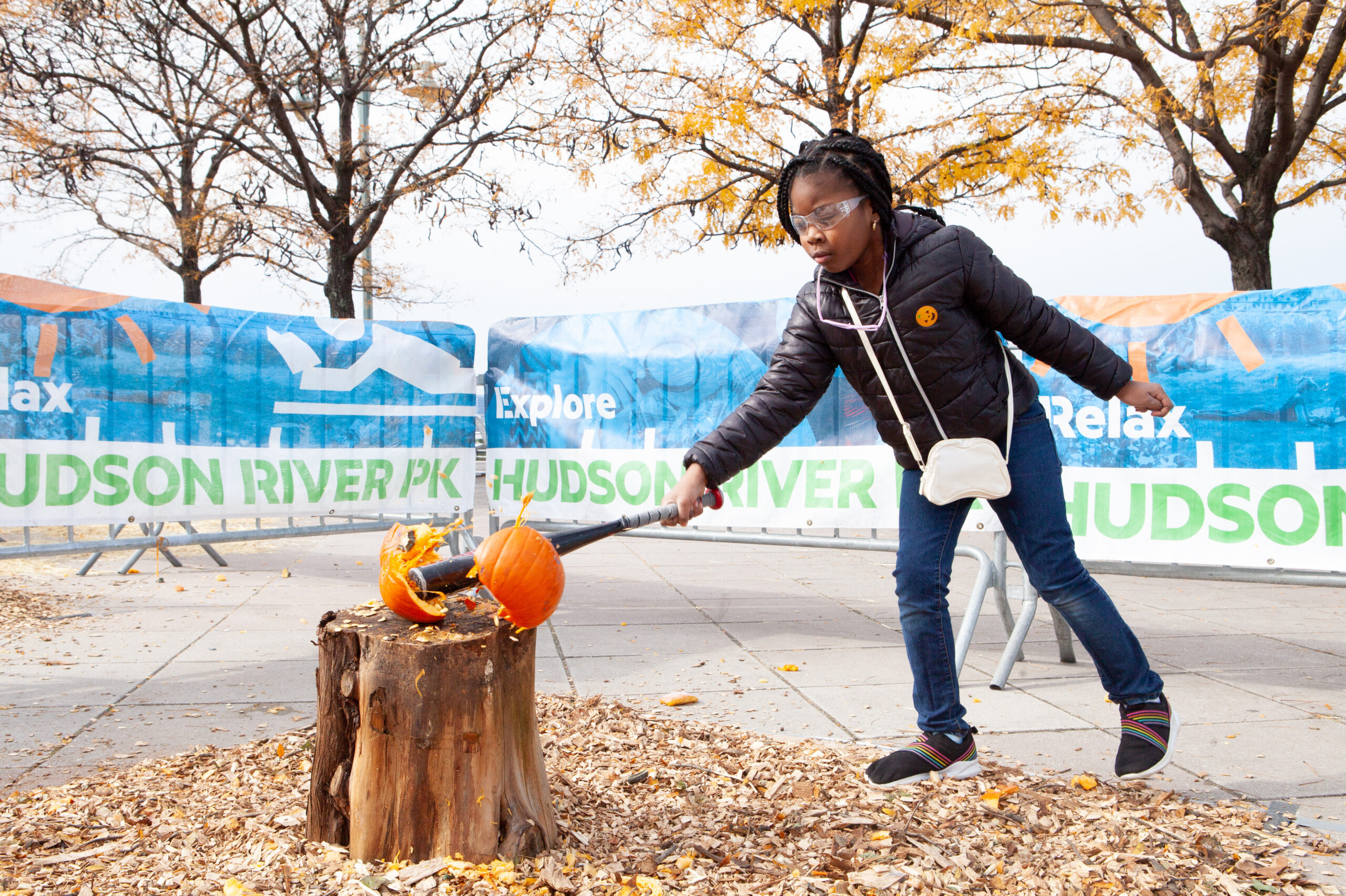 A child breaks a pumpkin open with a baseball bat during HRPK's Pumpkin Smash at Pier 84