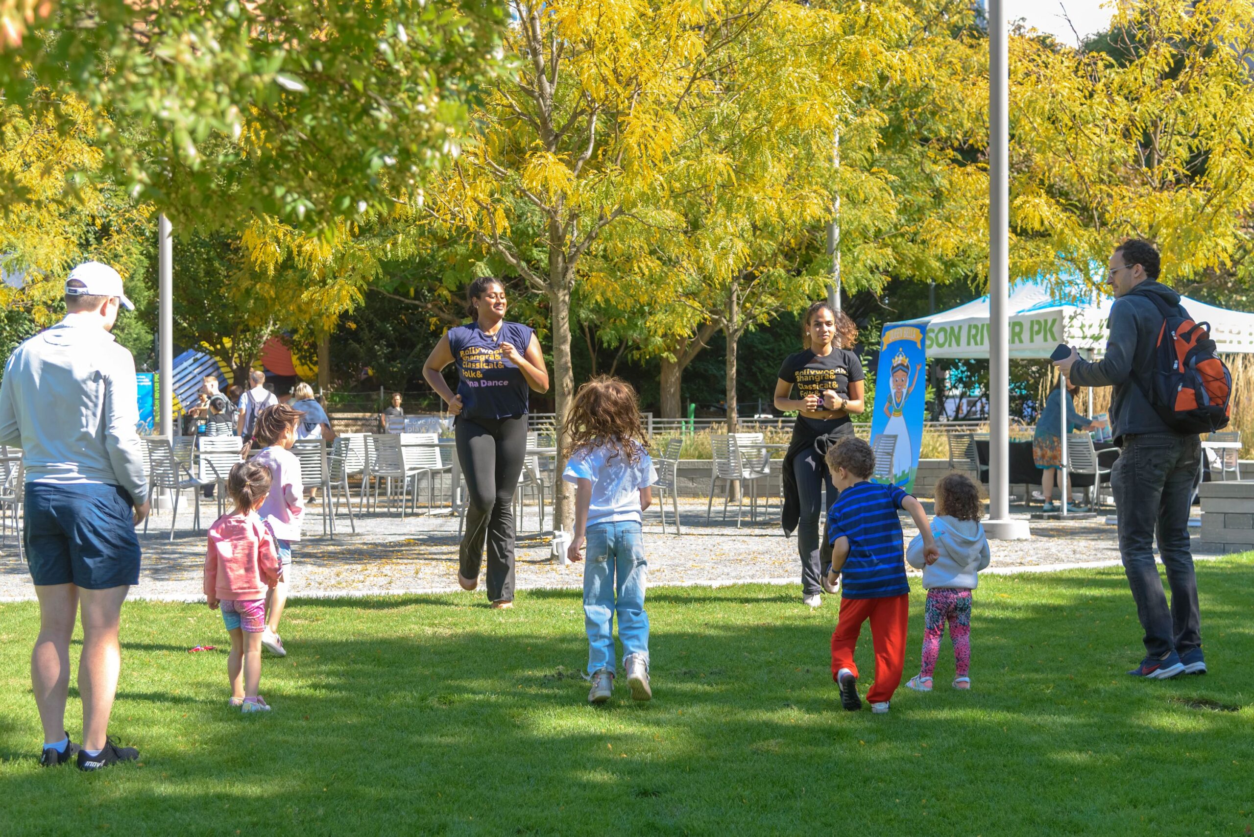 Two instructors from Ajna Dance Company lead children and adults in a dance class on the Chelsea Waterside lawn