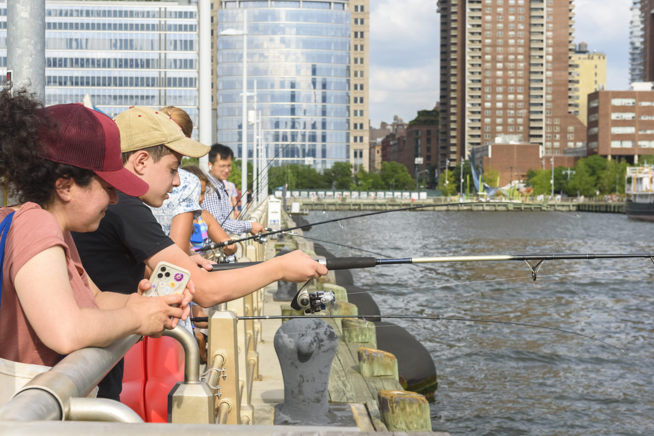 People holding fishing rods over the railing of Pier 25 during a Big City Fishing event