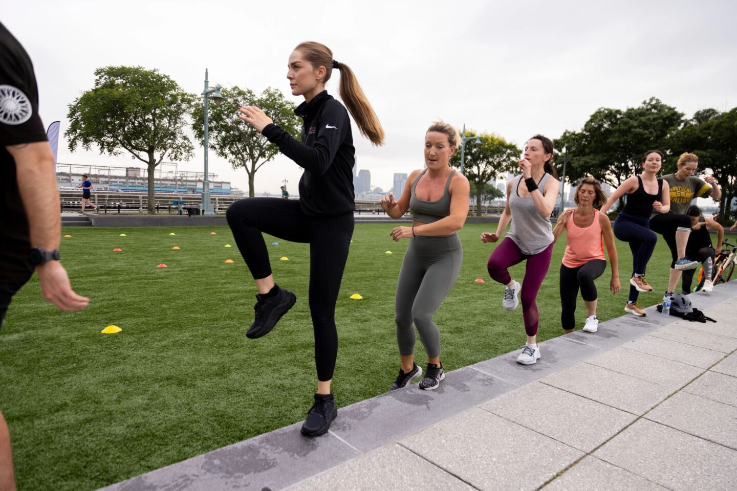 Healthy on the Hudson fitness class participants perform step-up exercises on the Pier 46 turf field