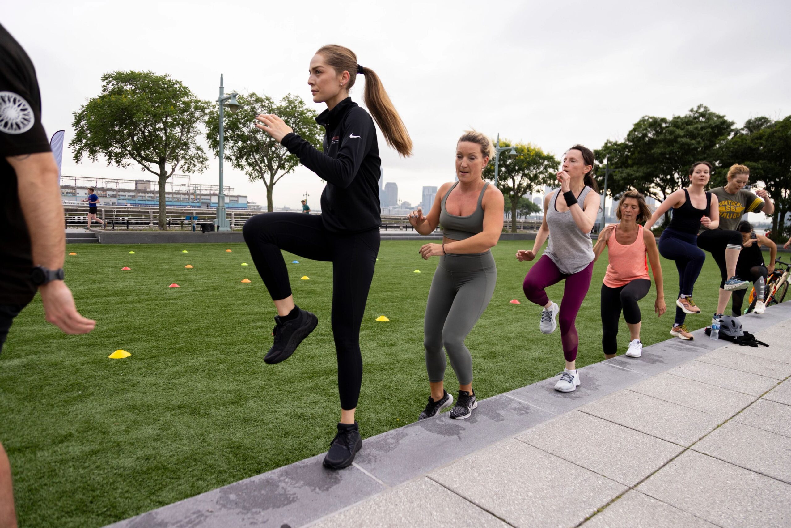 Healthy on the Hudson fitness class participants perform step-up exercises on the Pier 46 turf field