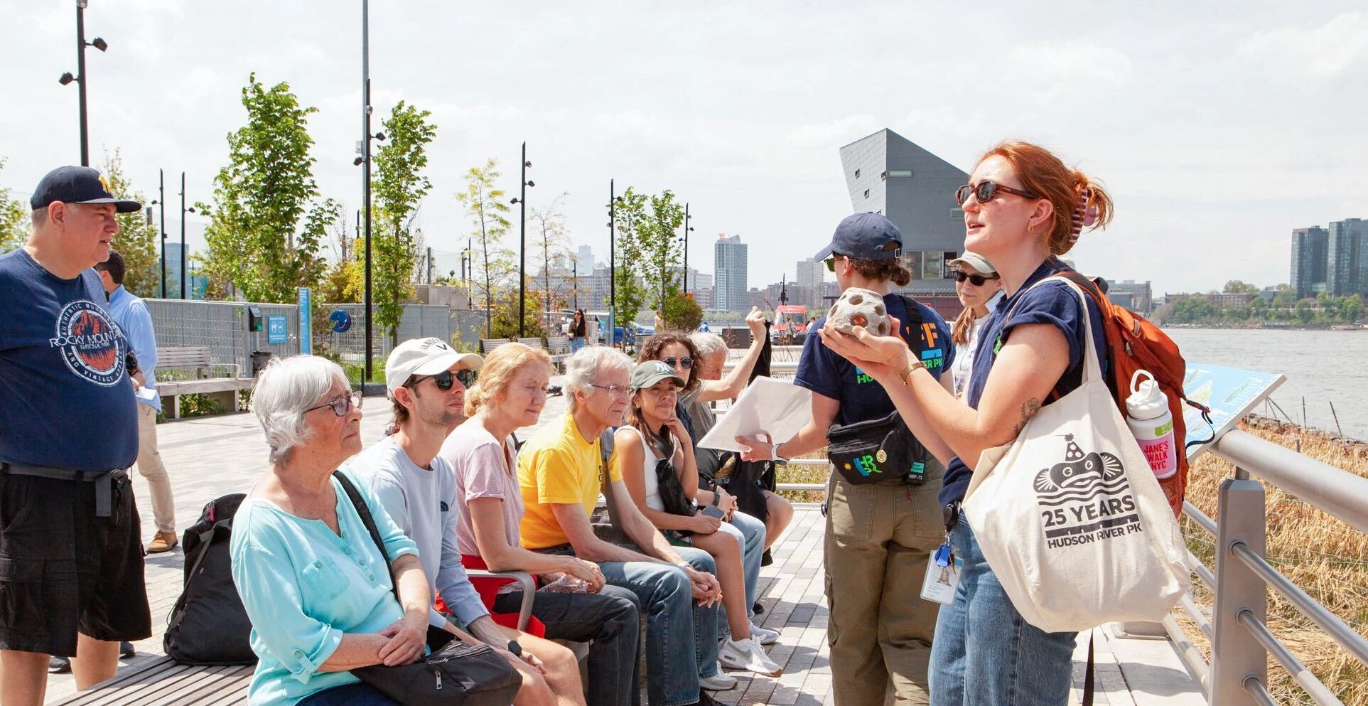 An HRPK River Project staffer holds a model of a reef ball up to show attendees of a Shoreline Strolls Park Tour at Gansevoort Peninsula