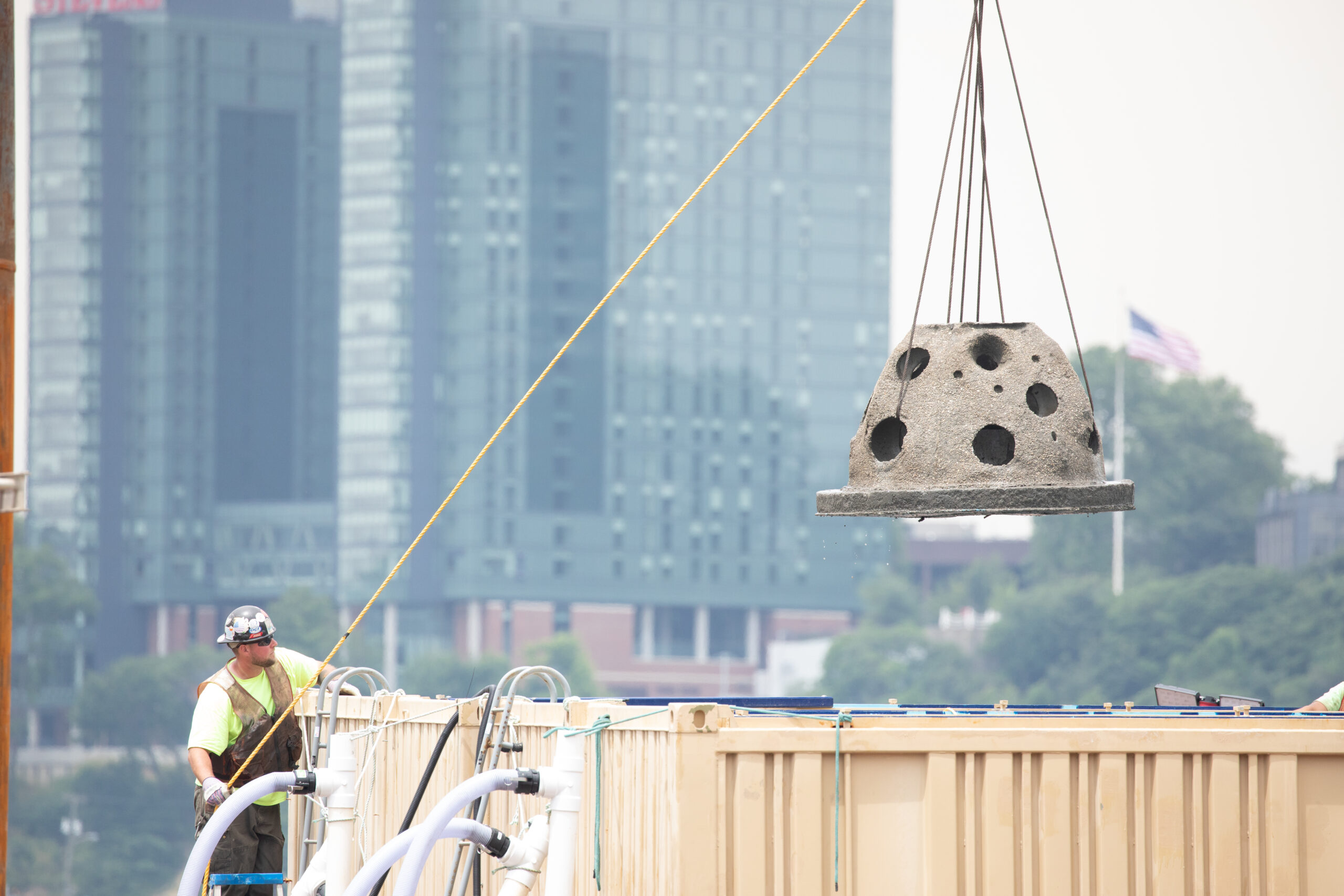A construction worker moves a reef ball on a cable