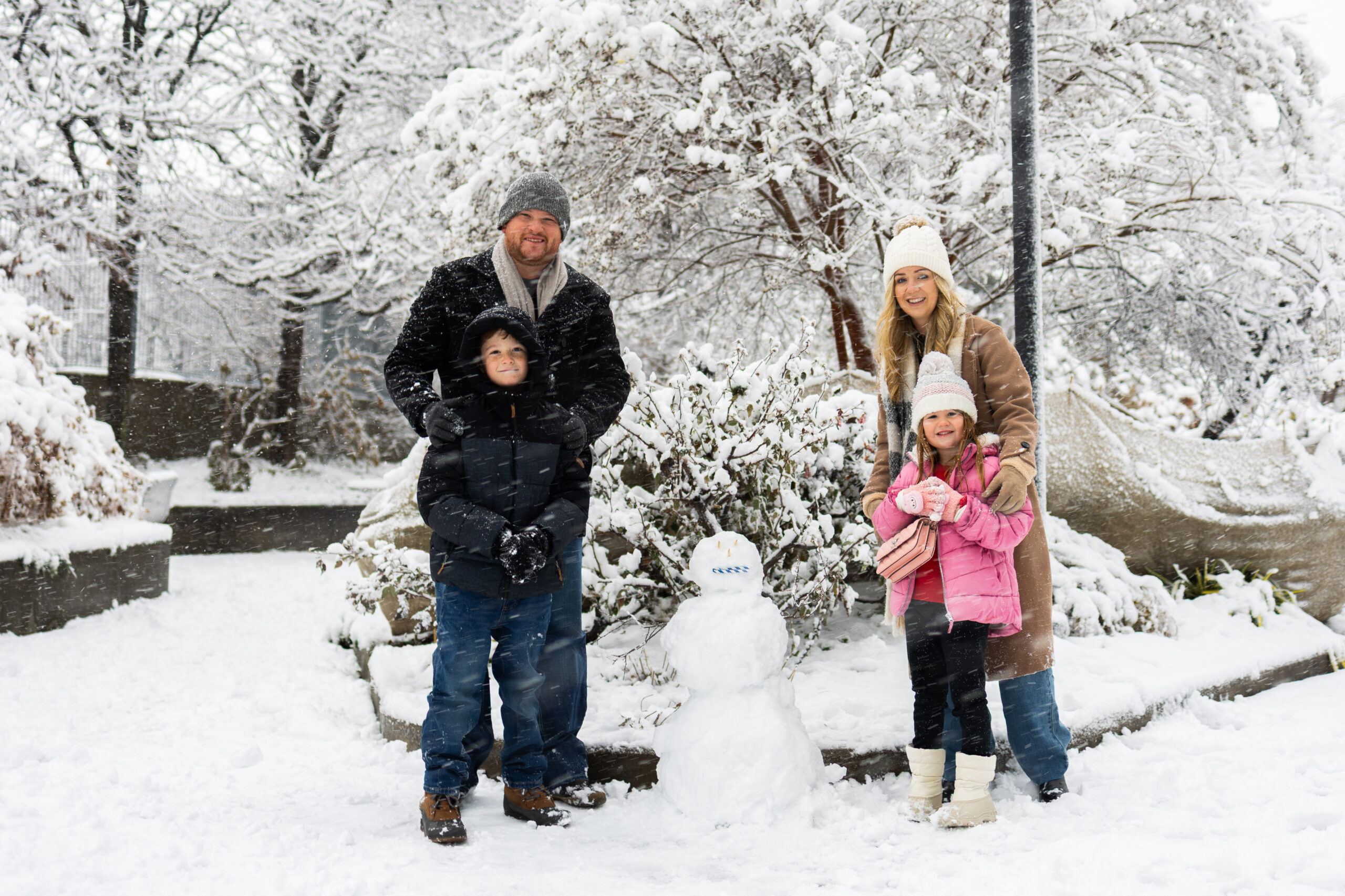 Family of four posing with snowman in Hudson River Park