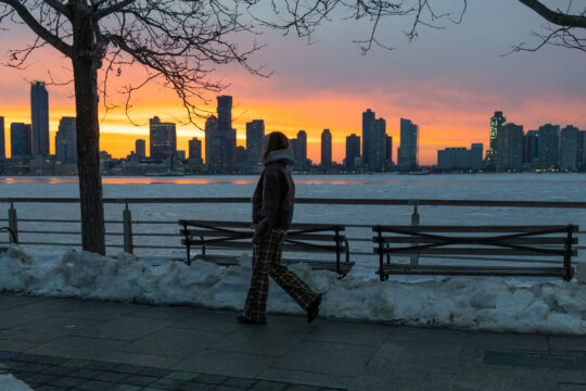 sunset over snowy waterfront, person walking, in Tribeca in Hudson River Park