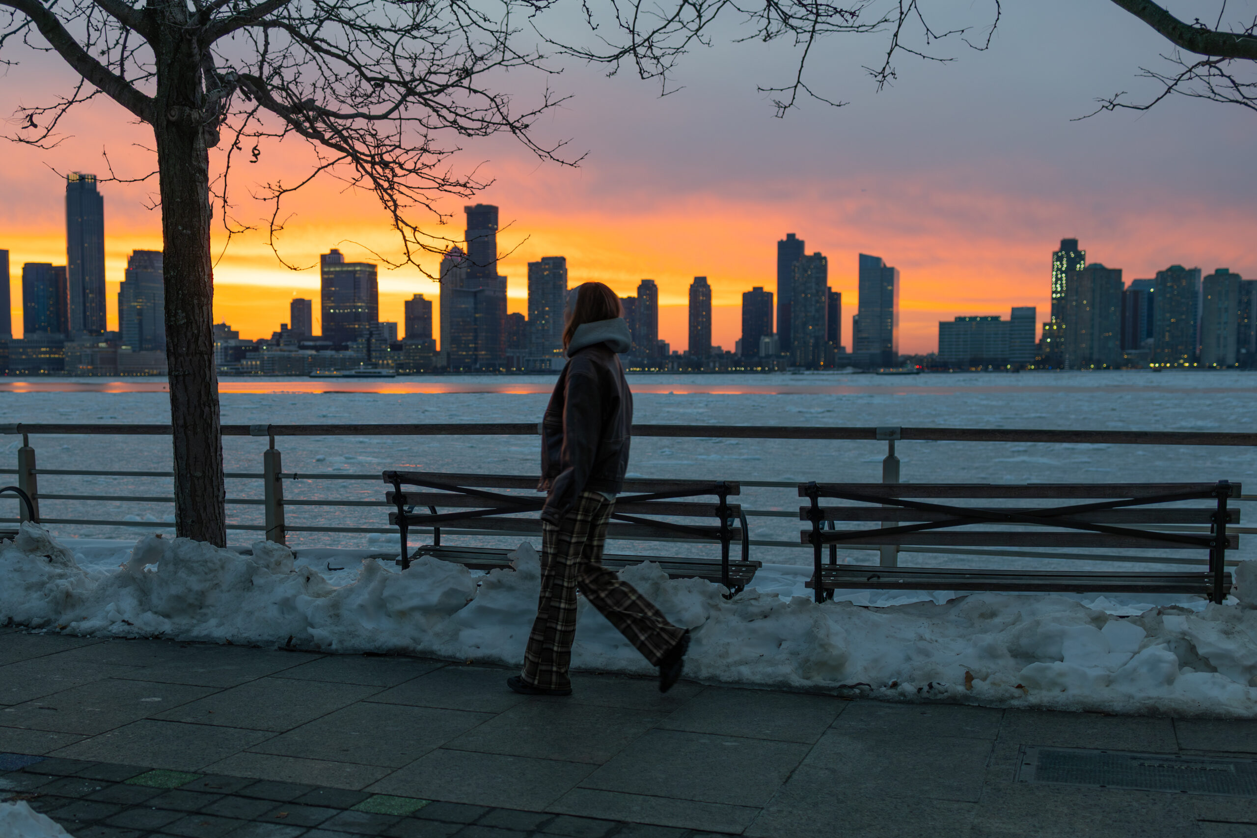 sunset over snowy waterfront, person walking, in Tribeca in Hudson River Park