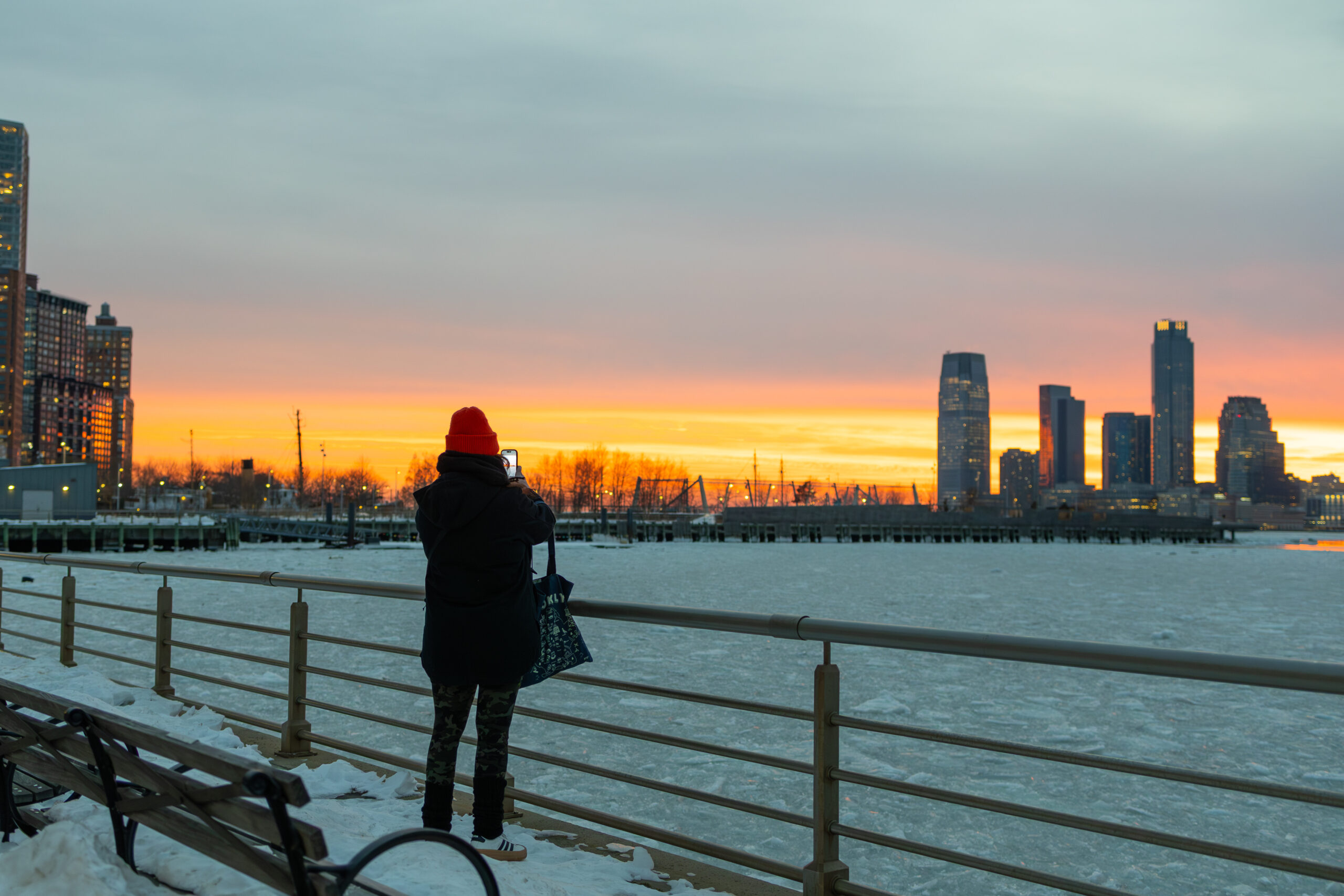 sunset over snowy waterfront, person taking photo, in Tribeca in Hudson River Park