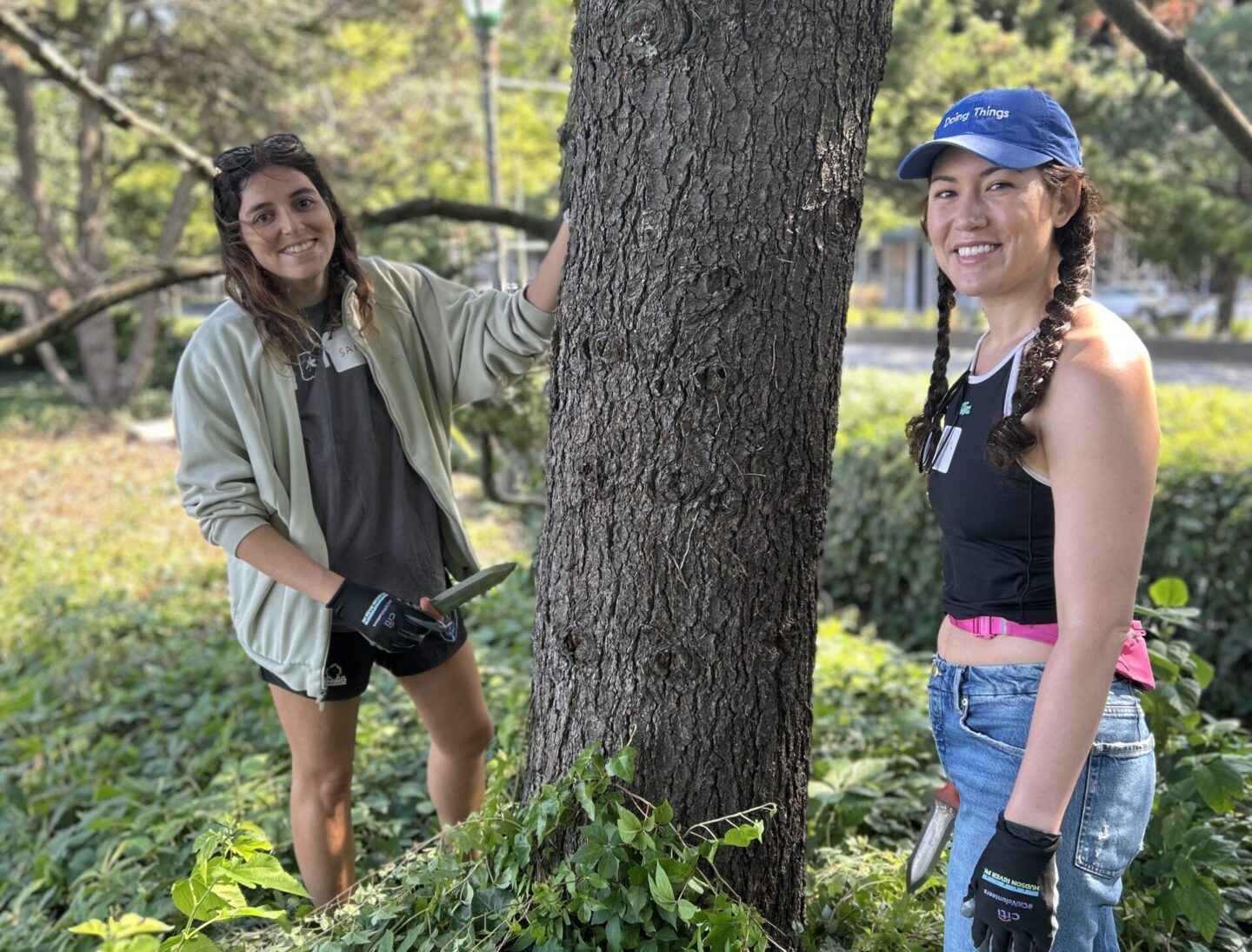 Volunteers at work in green space looking at camera smiling