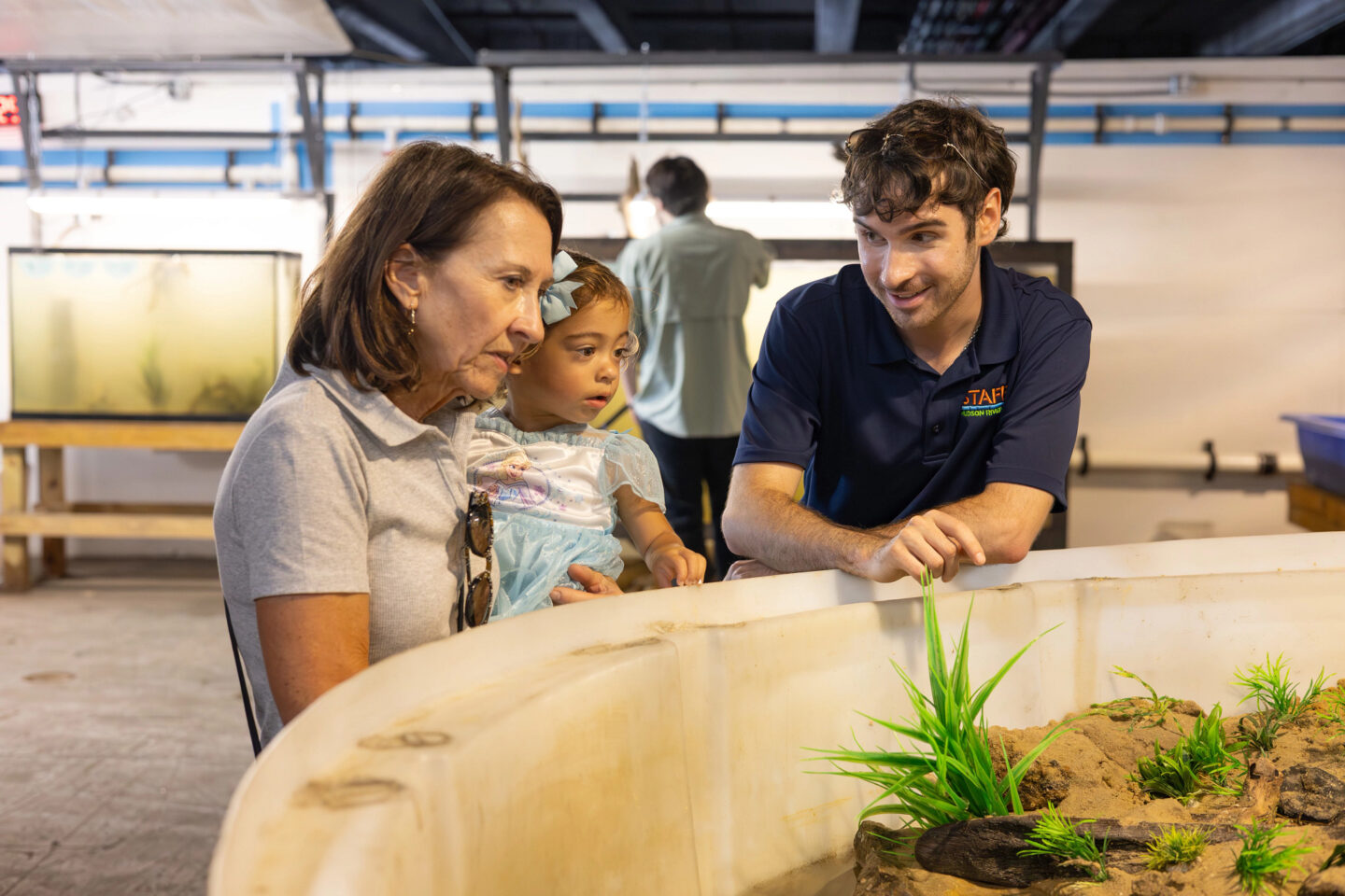 man, child, and woman looking at plant