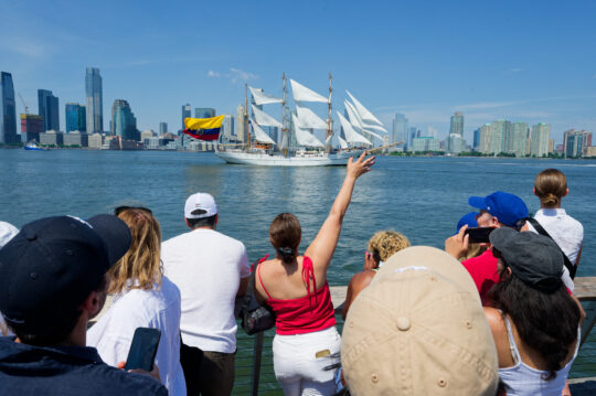 People wave to tall ship sailing on Hudson River