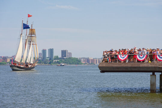 Crowds gathered at edge of Pier 26 with tall ship sailing by on Hudson River